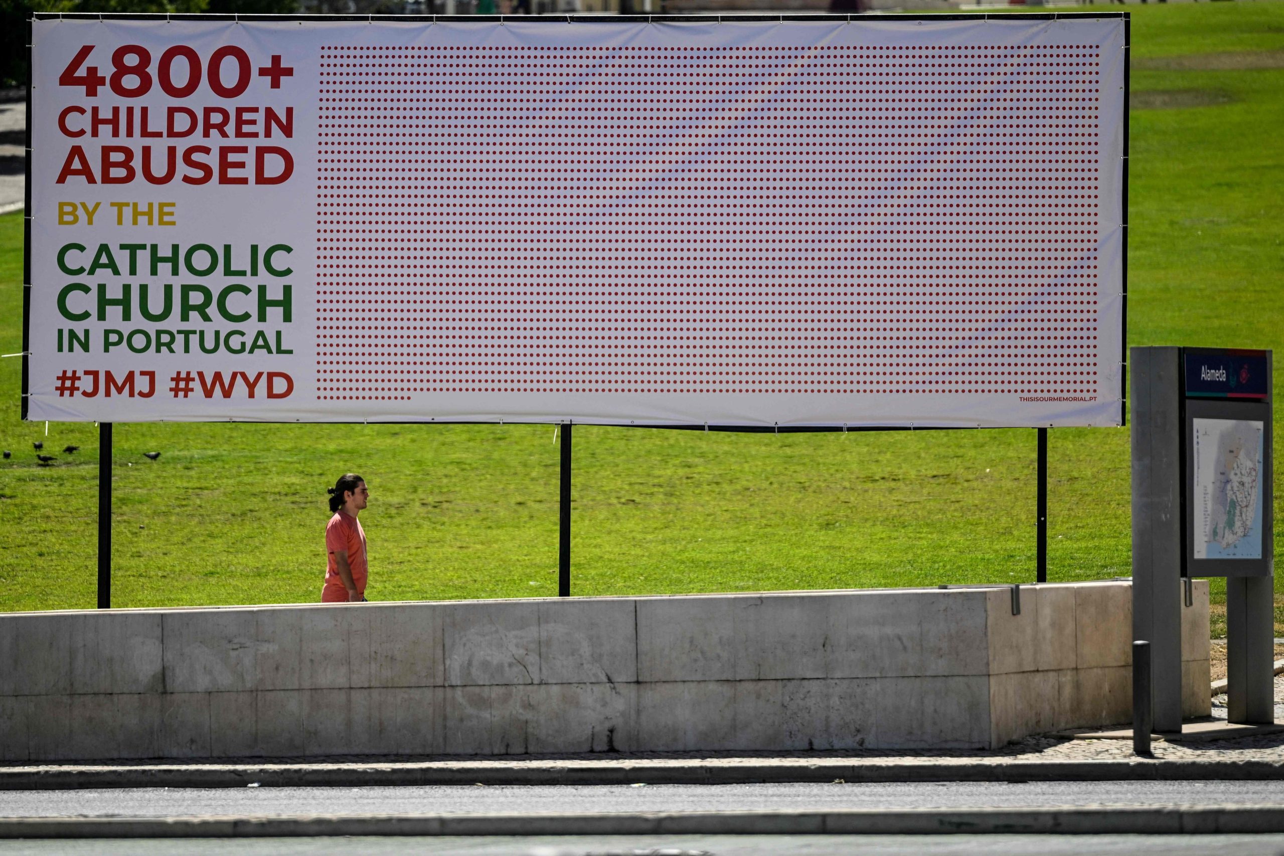 Un hombre pasa junto a un cartel que denuncia abusos sexuales por parte de miembros de la Iglesia católica portuguesa en la Alameda de Lisboa el 2 de agosto de 2023