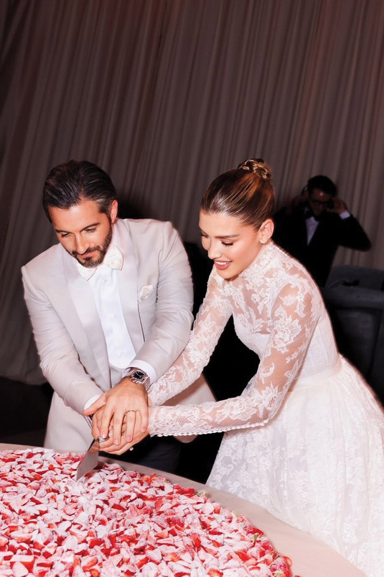 Los novios cortan la torta, decorada con frutas.