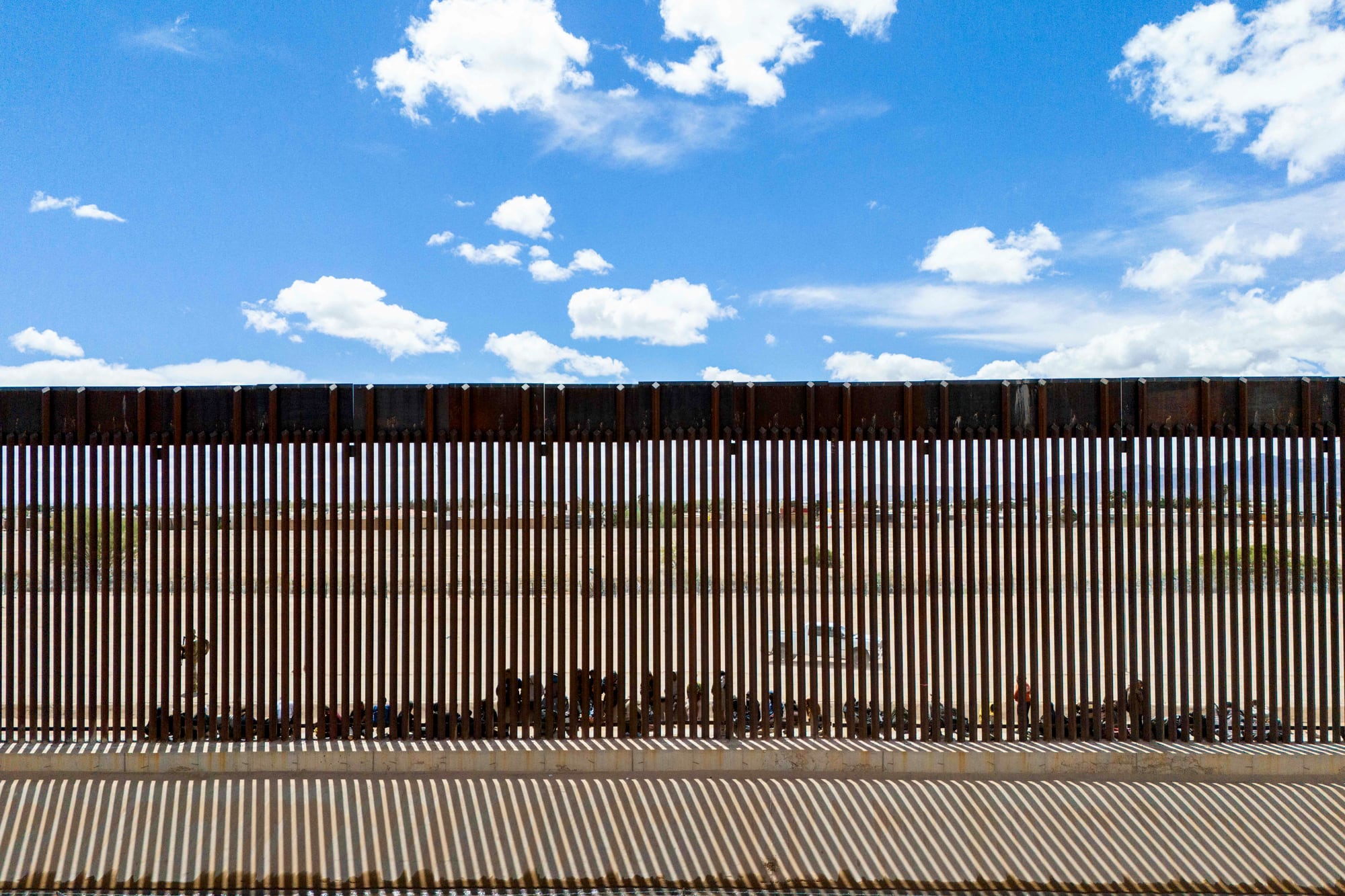 En una vista aérea, los migrantes que buscan asilo se agrupan junto a la valla fronteriza mientras esperan ser procesados ​​después de cruzar ilegalmente el río Grande hacia los Estados Unidos el 25 de marzo de 2024 en El Paso, Texas. 