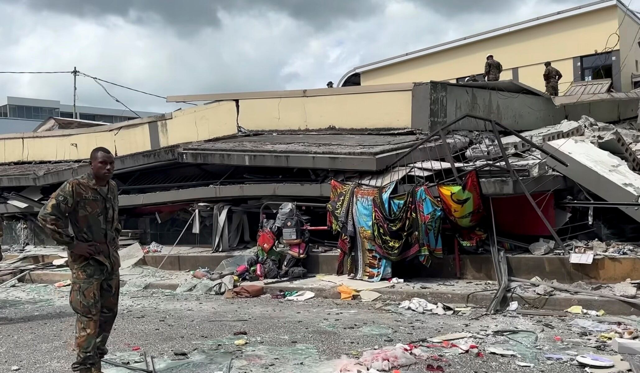 Una fotografía facilitada por Michael Thomson muestra una captura de pantalla de un vídeo en la que se ve a un soldado de pie junto a un edificio derrumbado tras un terremoto en Port Vila, Vanuatu (Foto: EFE)