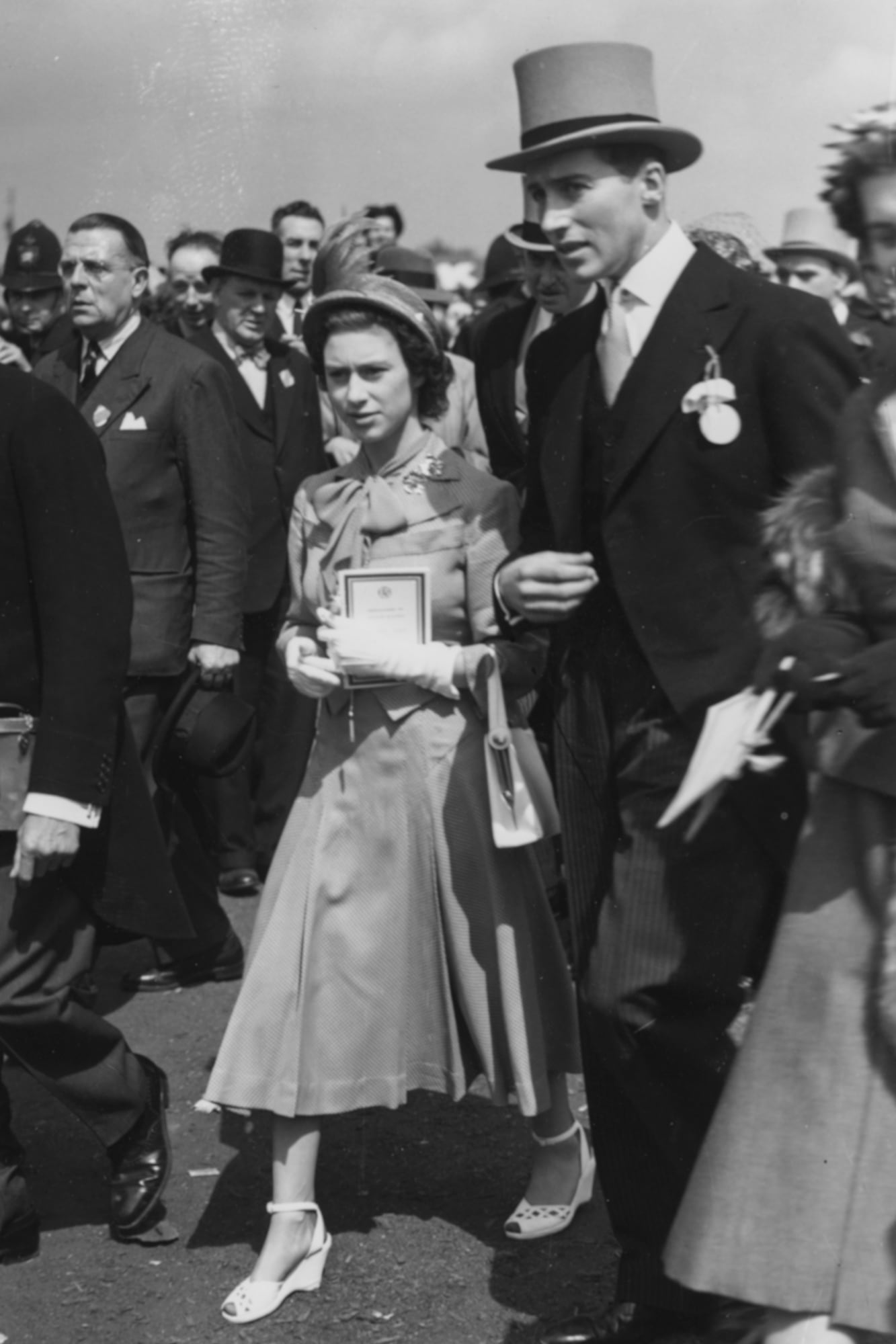 La entonces princesa Isabel y Lord Porchester caminando entre la genteen el hipódromo de Epsom, el 30 de mayo de 1951.