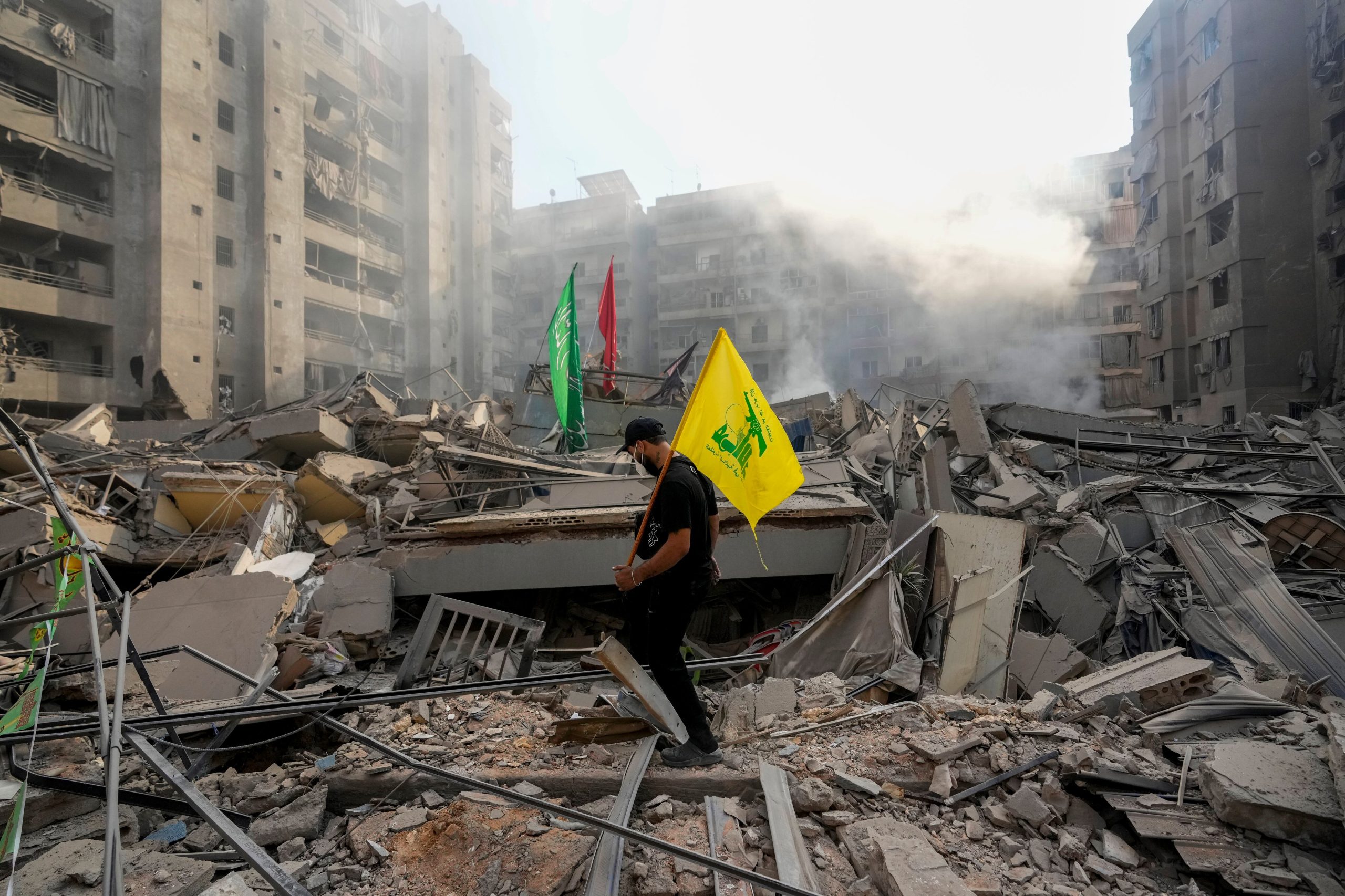 ARCHIVO - Un hombre porta una bandera de Hezbollah al caminar entre los escombros de su apartamento destruido durante un ataque aéreo israelí, en el Líbano, el 1 de noviembre de 2024. (AP Foto/Hassan Ammar, archivo)