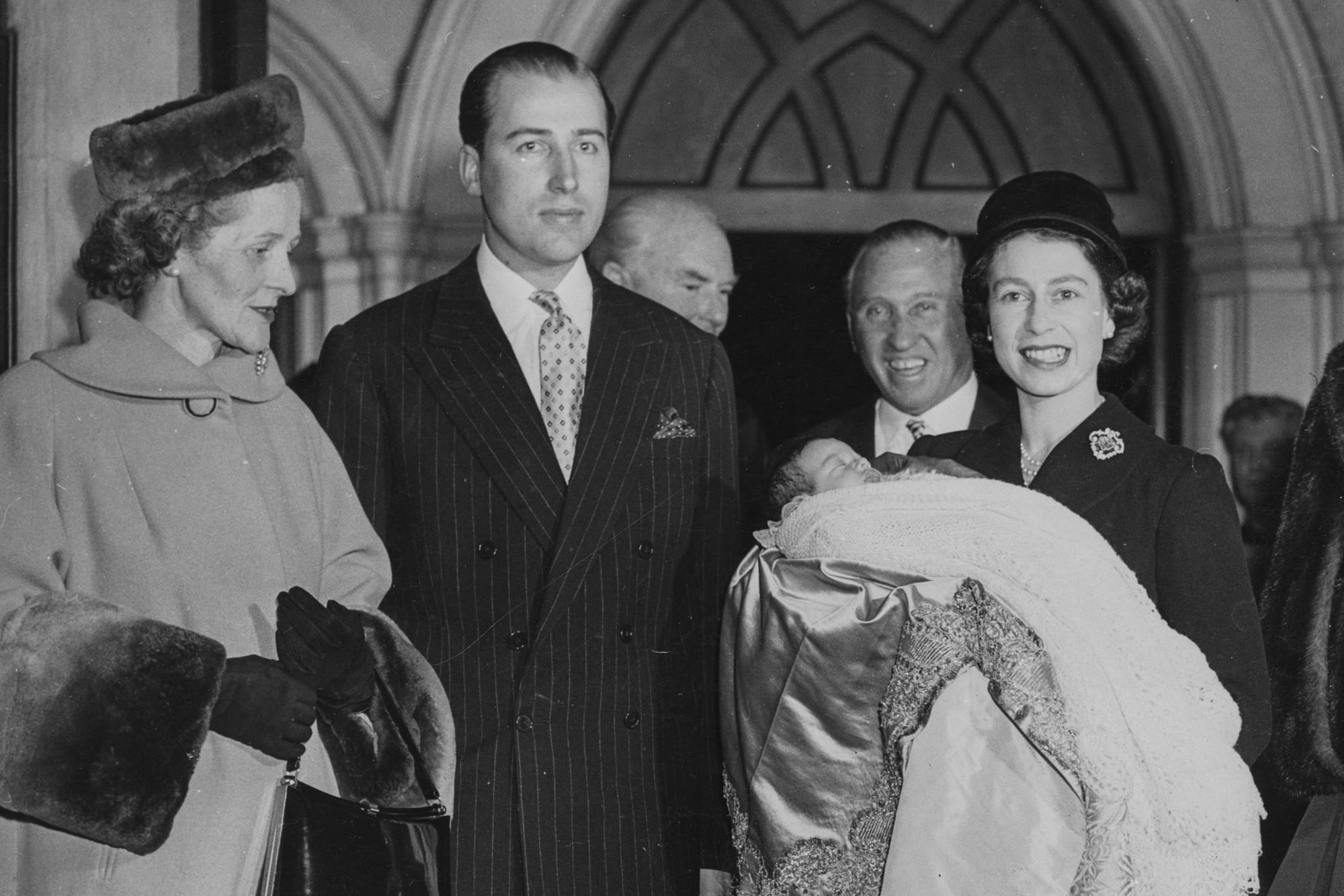 Isabel II sostiene en brazos a su ahijado George, hijo de Lord Porchester, después de su bautismo en St Paul’s, en Knightsbridge, Londres, en diciembre de 1956. En ese momento llevaba cuatro años en el trono.