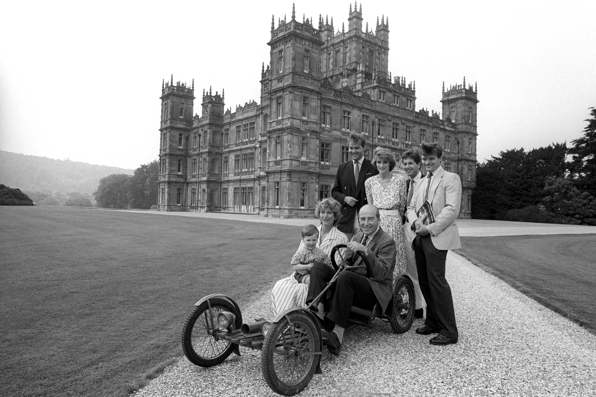 En el castillo de Highclere, cerca de Newbury, el séptimo conde de Carnarvon se sienta en el Red Bug Buckboard familiar de 1922, rodeado por su familia y listo para recibir a los visitantes cuando su casa se abra al público por primera vez. Es el 3 de julio de 1988. De pie, de izquierda a derecha: Lord Porchester, 31 años, hijo mayor y heredero; su hija Lady Carolyn Warren, de 26 años, su esposo John y su hijo, Harry Herbert. La condesa de Carnarvon sostiene a su nieto Jake, hijo de Lady Carolyn.