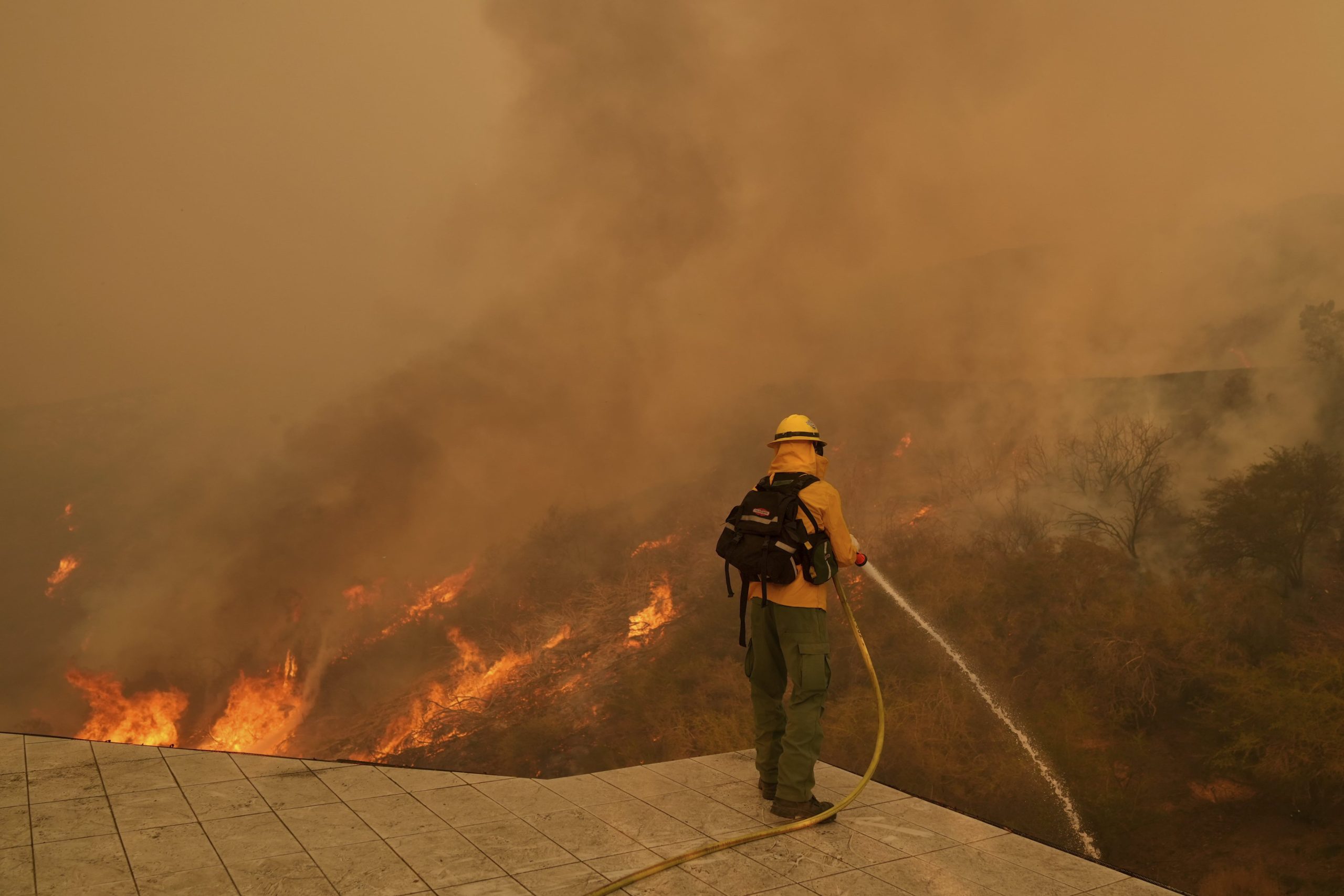 Un bombero apaga las llamas con una manguera mientras el incendio Palisades se acerca en Mandeville Canyon el sábado 11 de enero de 2025 en Los Ángeles