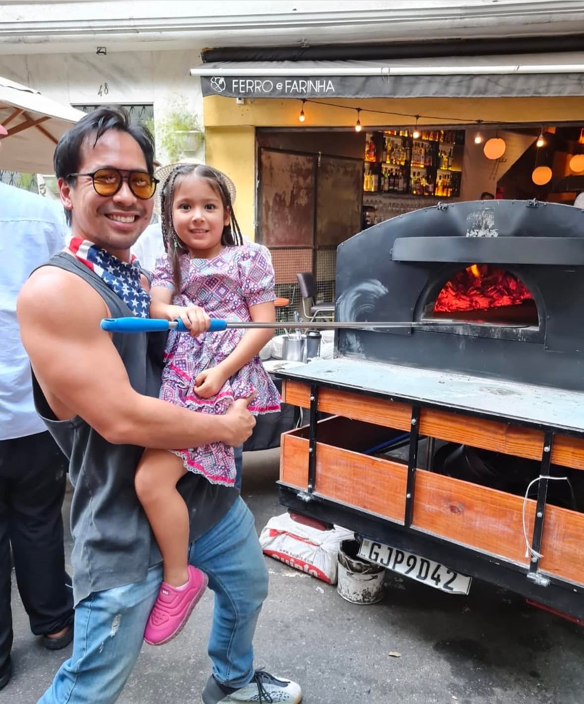 Sei y su hija en el horno a leña ambulante con el que empezó a cocinar.