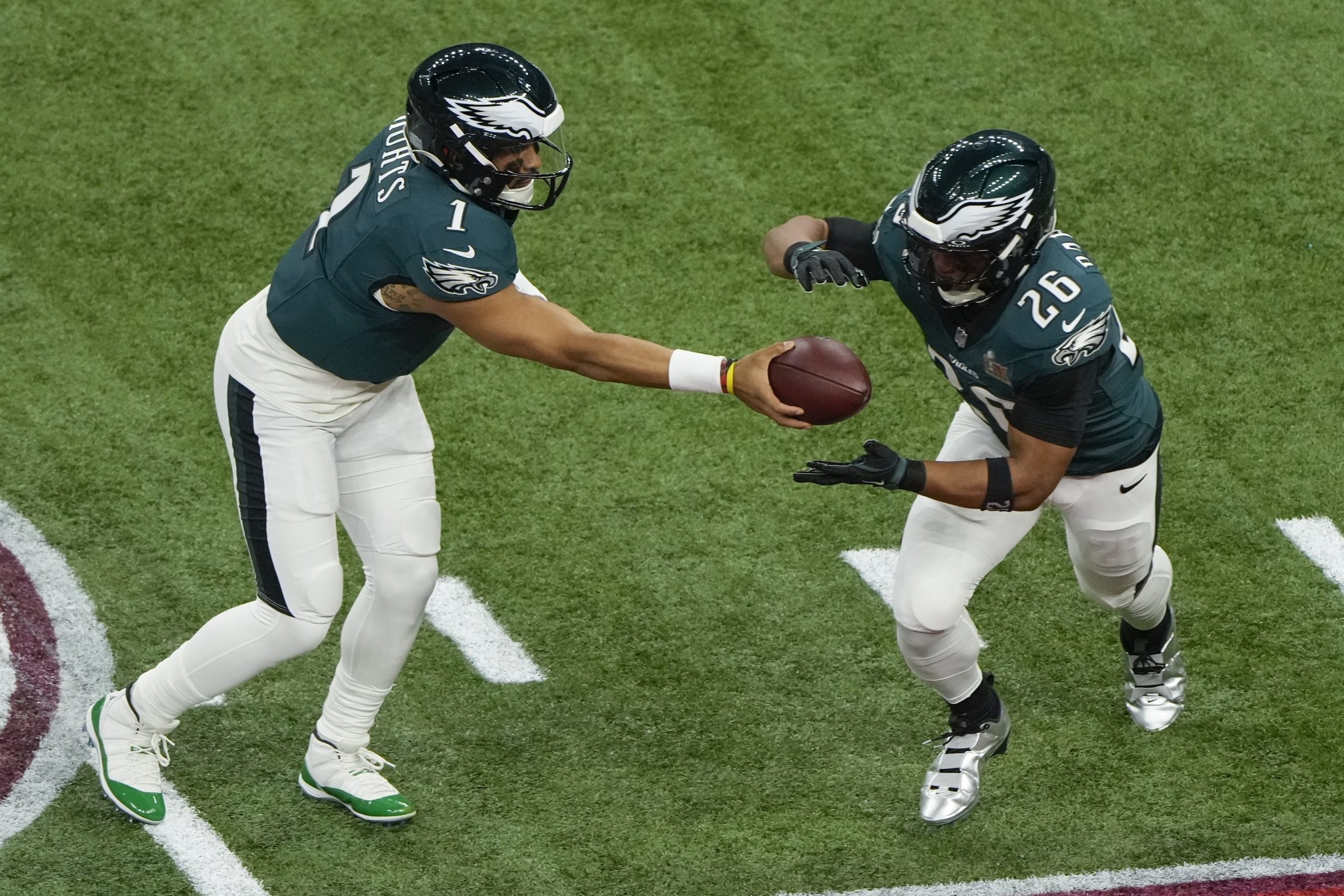 Philadelphia Eagles quarterback Jalen Hurts (1) hands off to running back Saquon Barkley (26) during the first half of the NFL Super Bowl 59 football game against the Kansas City Chiefs, Sunday, Feb. 9, 2025, in New Orleans. (AP Photo/Charlie Riedel)