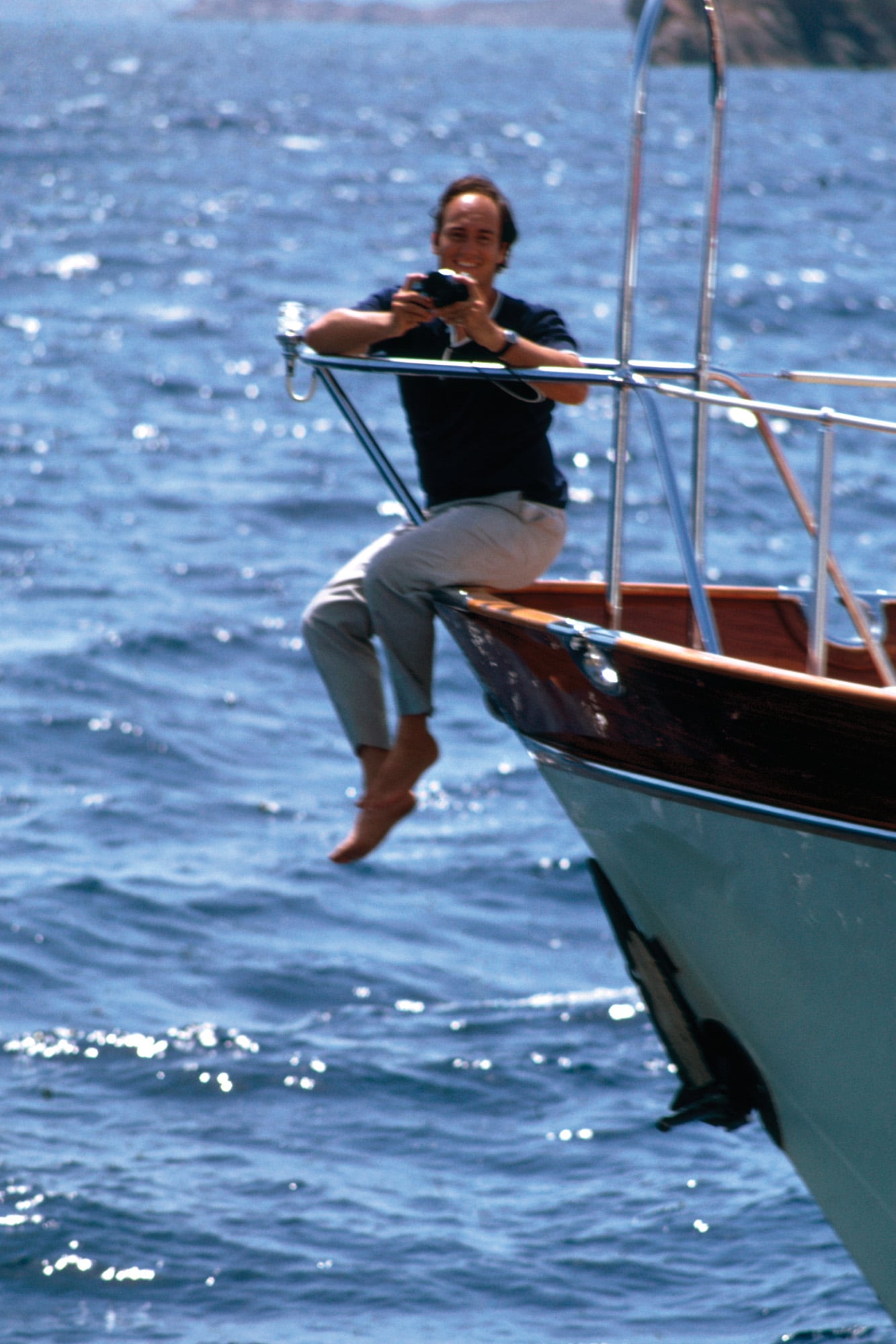 Tomando fotos sentado en la proa de su yacht anclado en la Costa Esmeralda, Cerdeña (1967). 