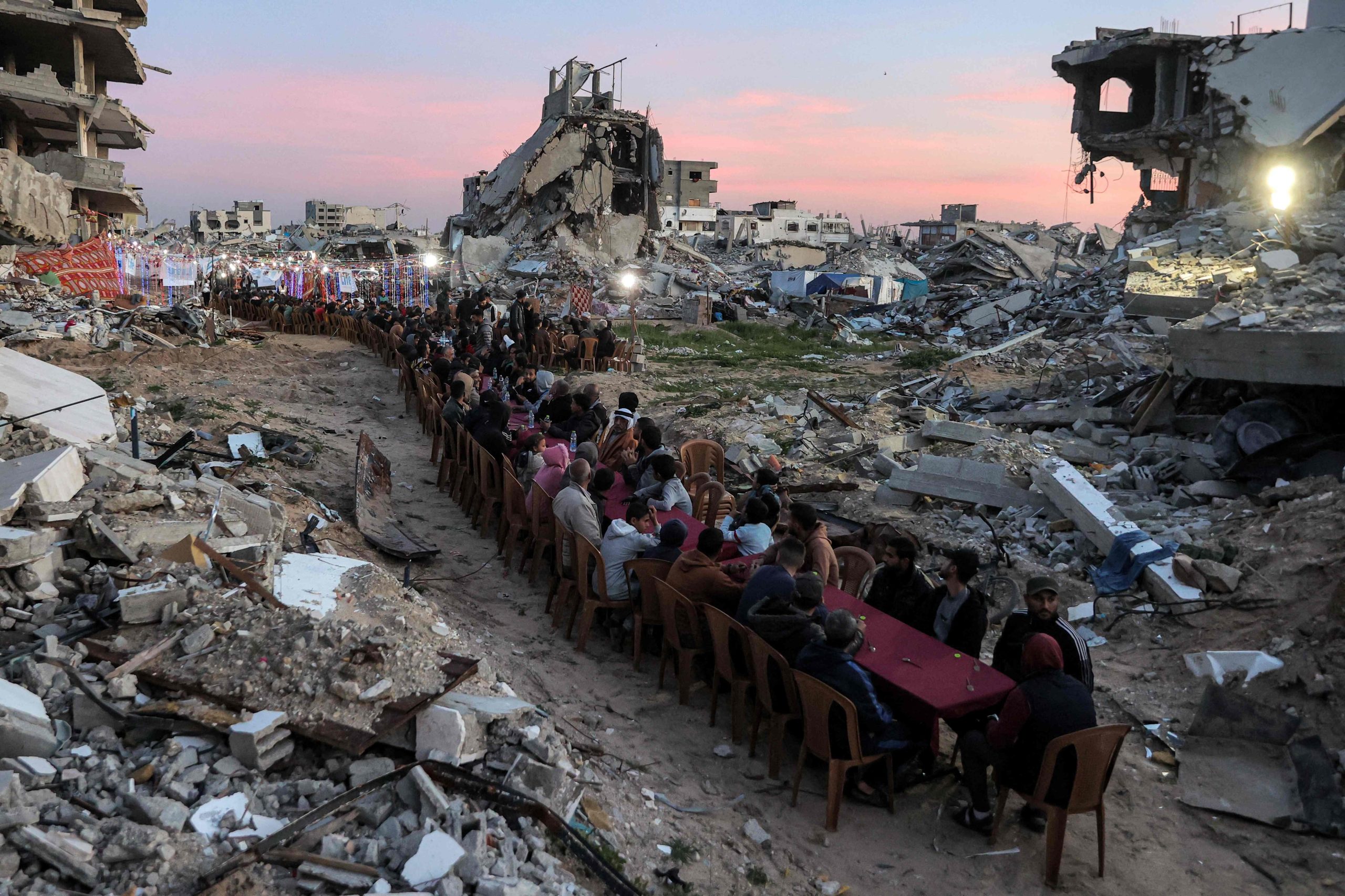 Reunión entre los escombros de los edificios destruidos para una reunión masiva para una comida comunitaria de ruptura del ayuno iftar en el segundo día del mes sagrado musulmán del Ramadán en el área de al-Dahduh en el distrito de Tal al-Hawa de la ciudad de Gaza el 2 de marzo de 2025 en medio de la tregua en curso en la guerra entre Israel y Hamas. (Photo by Omar AL-QATTAA / AFP)