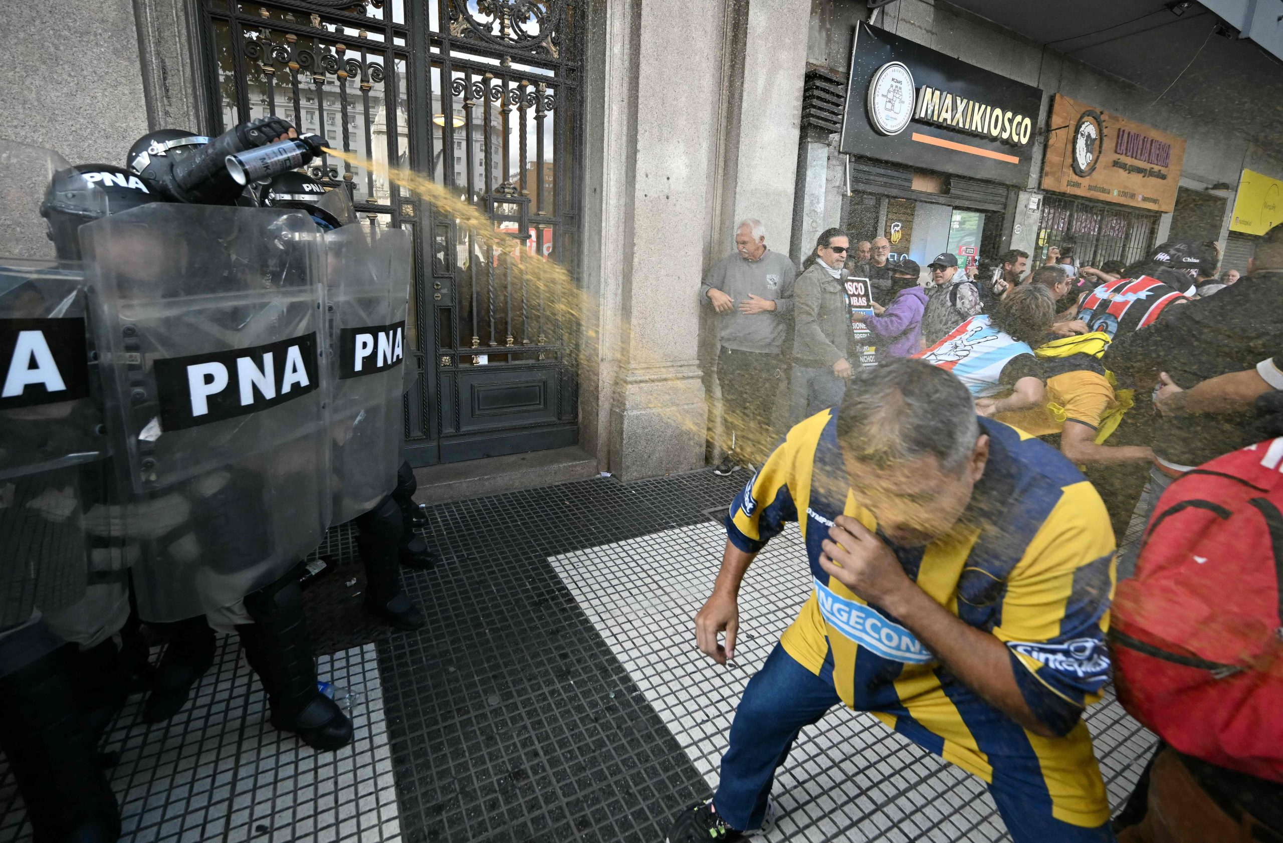 Un policía aplica spray de pimienta a un partidario de Rosario Central durante una protesta de jubilados