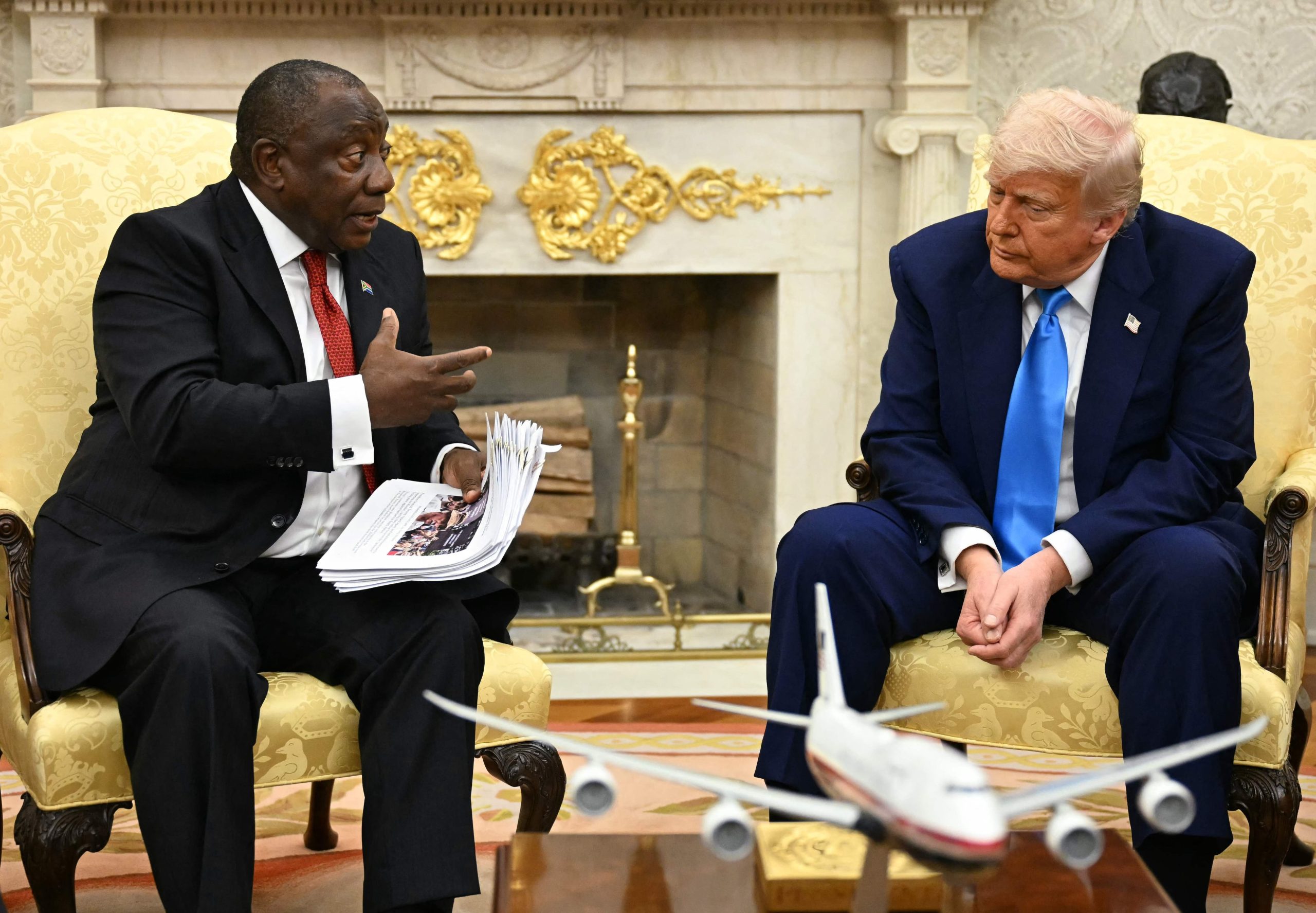 El presidente estadounidense Donald Trump entrega documentos al presidente sudafricano Cyril Ramaphosa durante una reunión en la Oficina Oval 