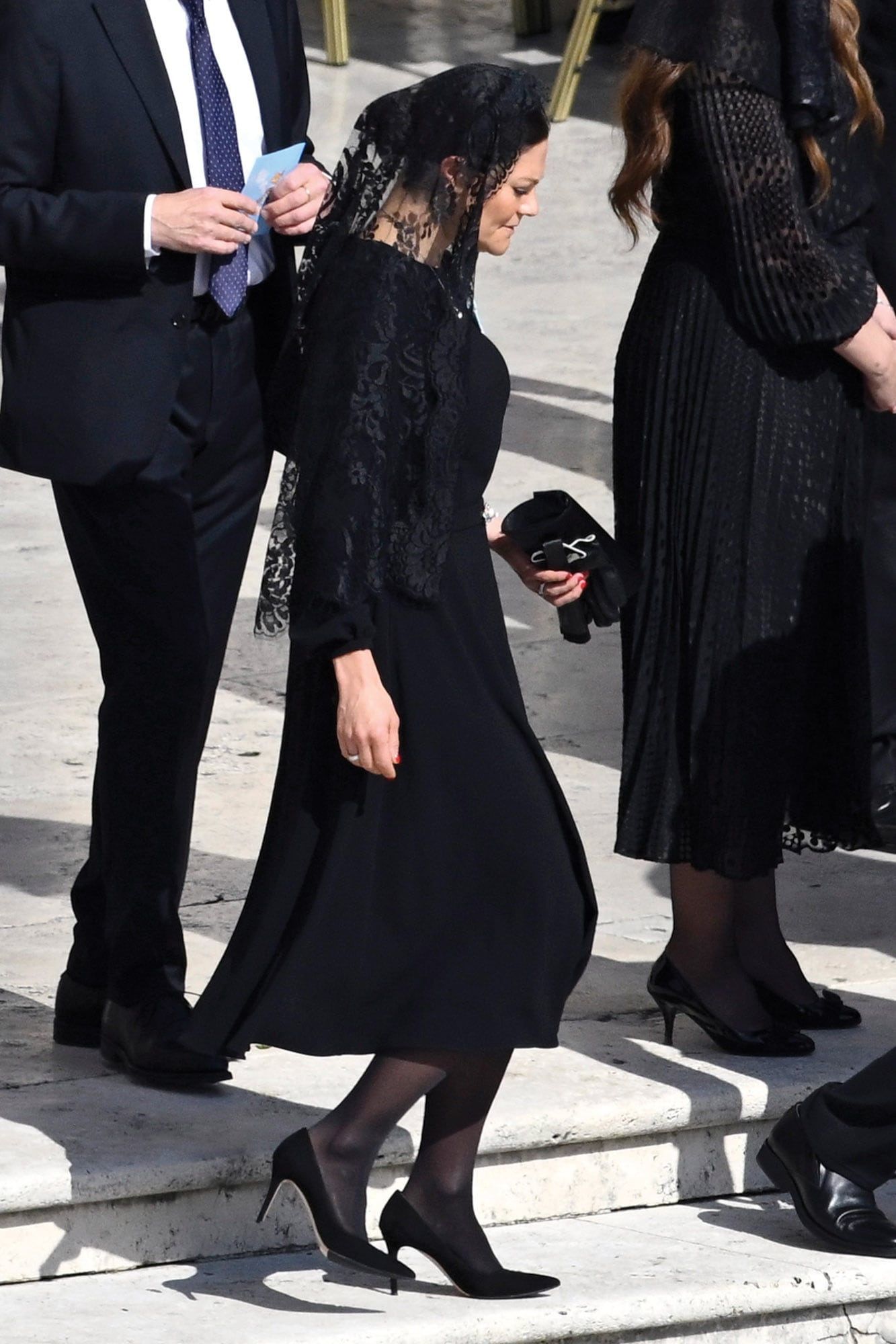 La princesa Victoria de Suecia, con un vestido midi de líneas rectas; llevó medias negras, stillettos Gianvito Rossi, mantilla y guantes, que optó por sacarse. 