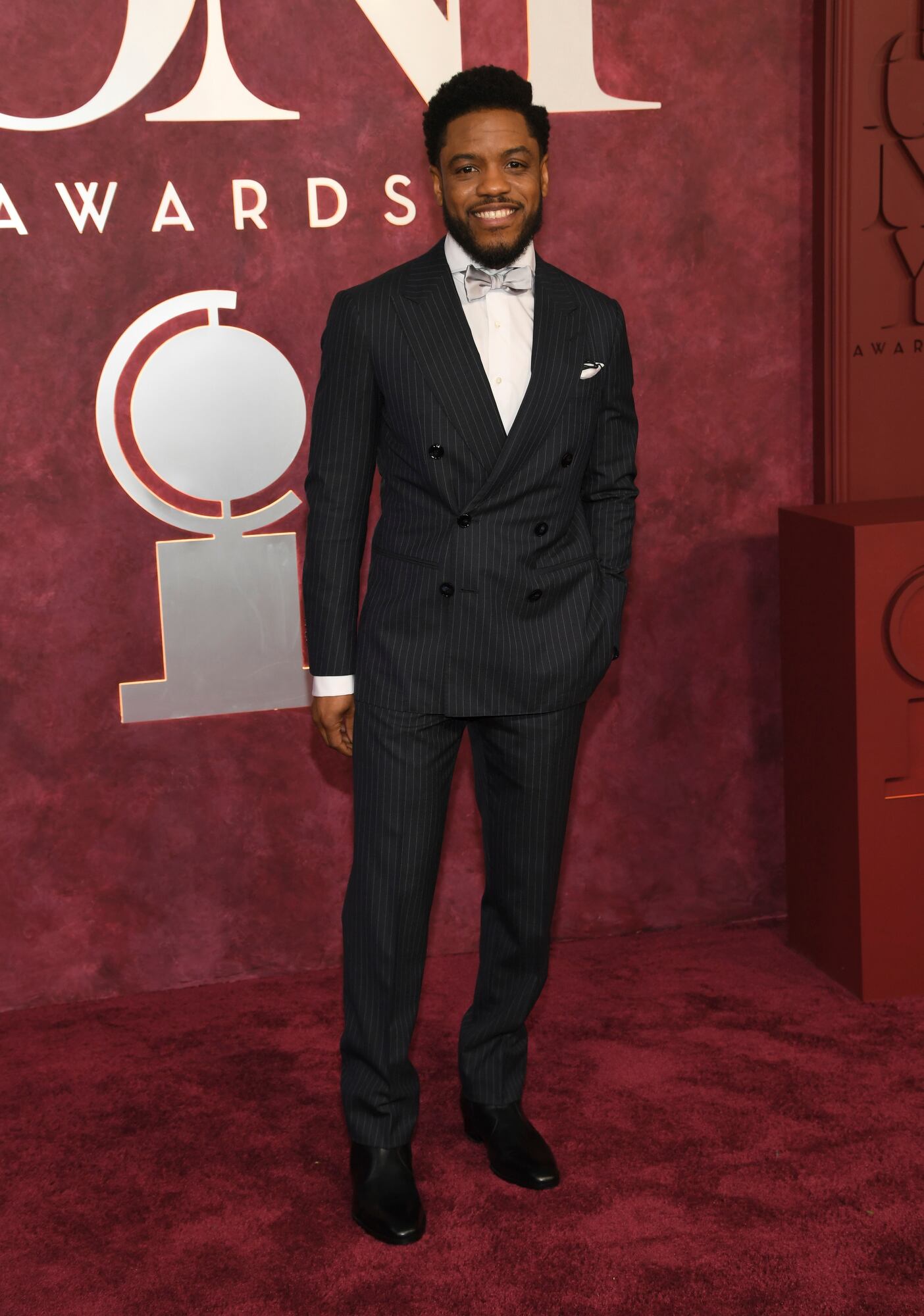 Jon Michael Hill con un traje a rayas y moño plateado
