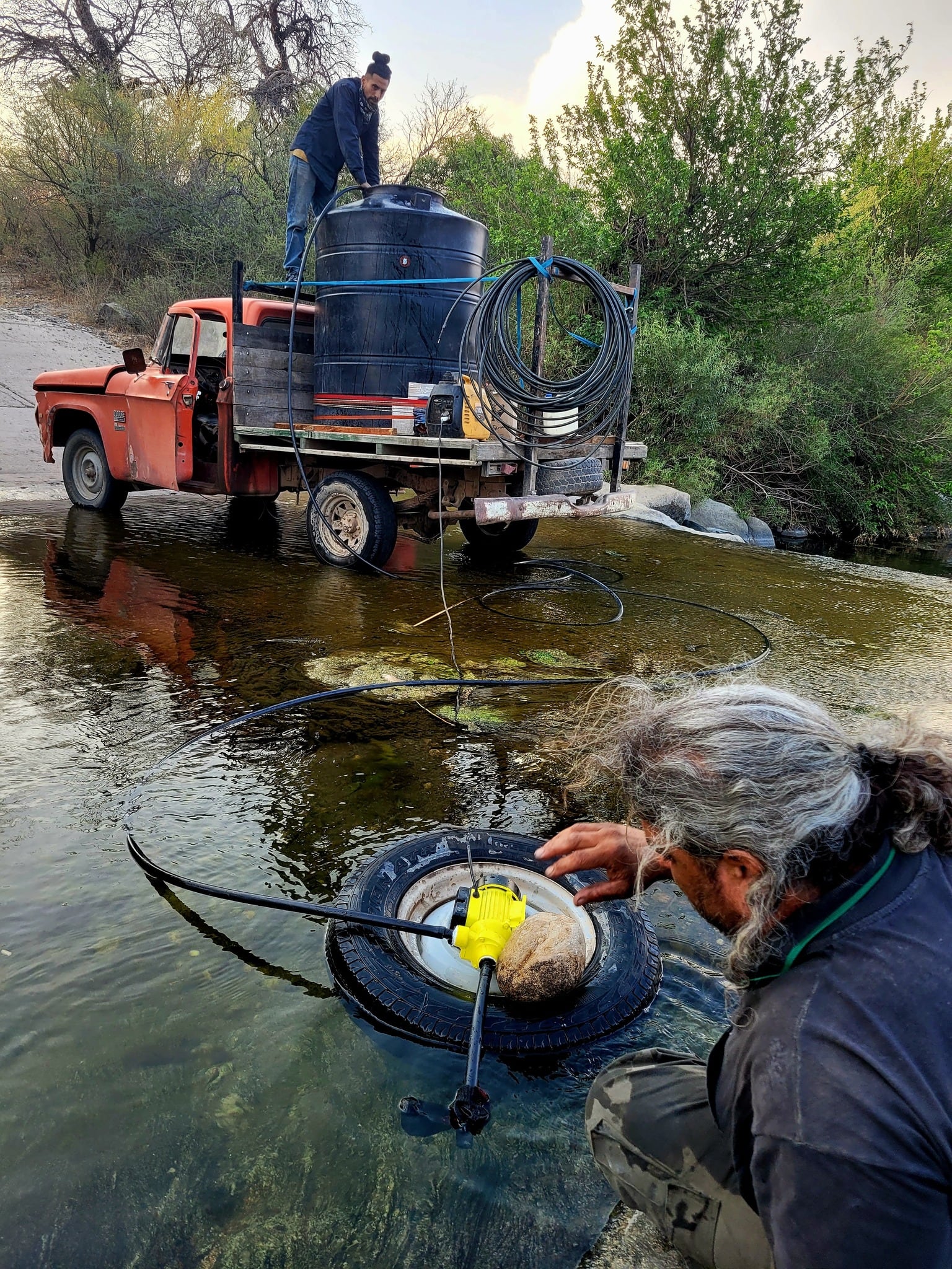 Burgos cargando agua en el tanque hidrante que improvisó en su camioncito