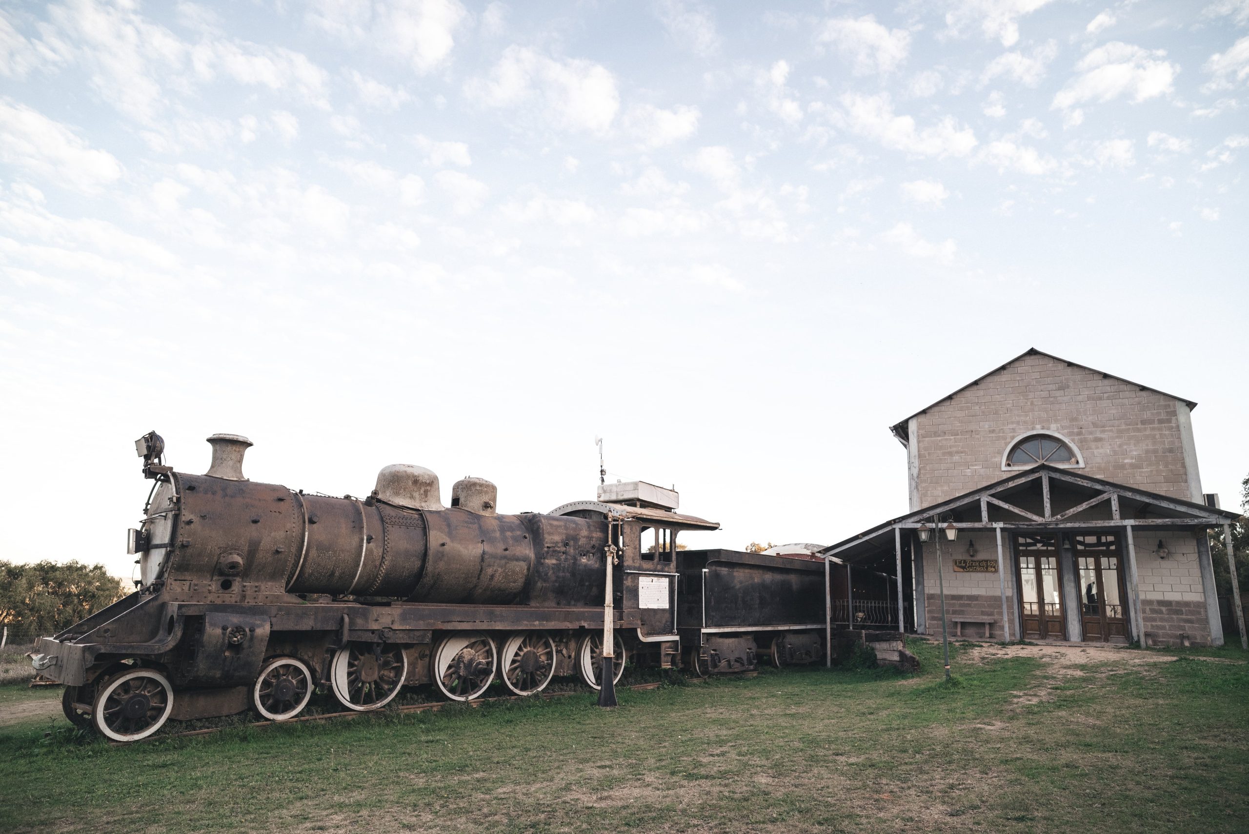 La locomotora y el vagón están estacionados en el andén que antecede la réplica de una estación.