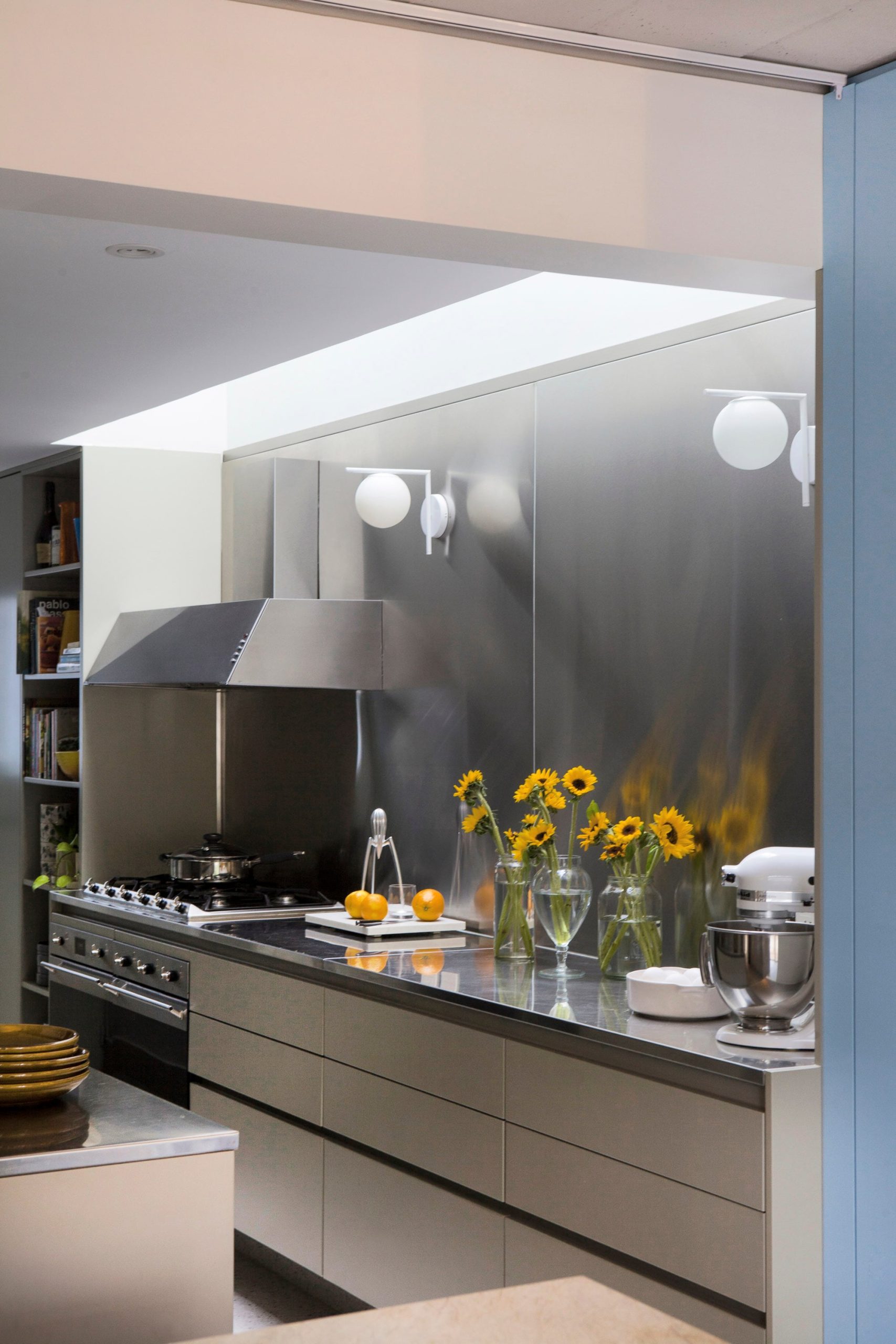 Cocina revestida en acero inoxidable (Versatile). Muebles laqueados en gris semi mate platino, de la paleta de Dwell. Apliques L (Gled Store).