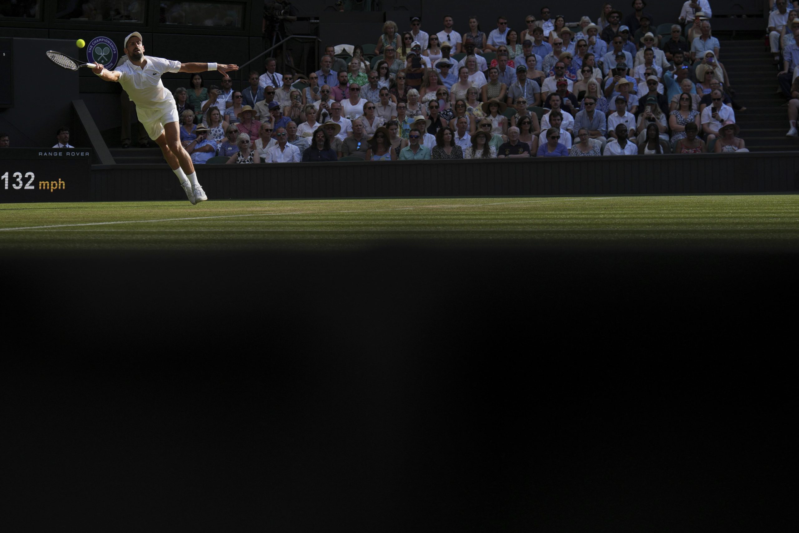 El serbio Novak Djokovic intenta responder un saque del italiano Jannik Sinner durante el partido entre ambos por las semifinales de Wimbledon