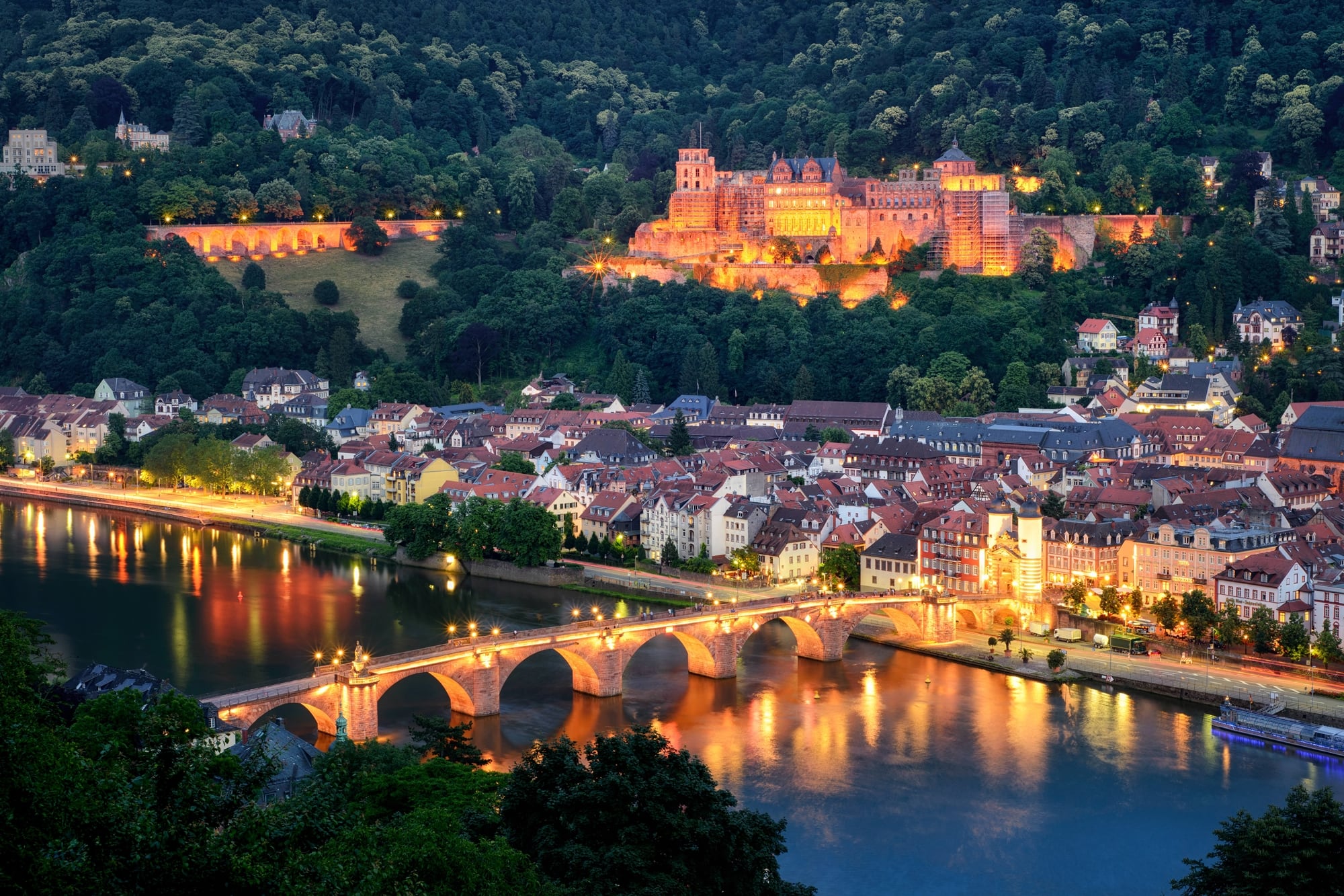 Vista nocturna de la ciudad universitaria de Heidelberg y su imponente castillo iluminado.