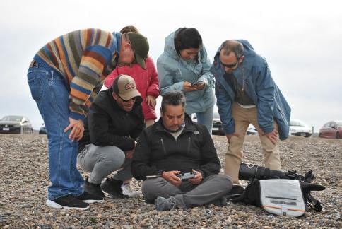 El fotógrafo revisa su cámara con un grupo de curiosos en la playa El Doradillo