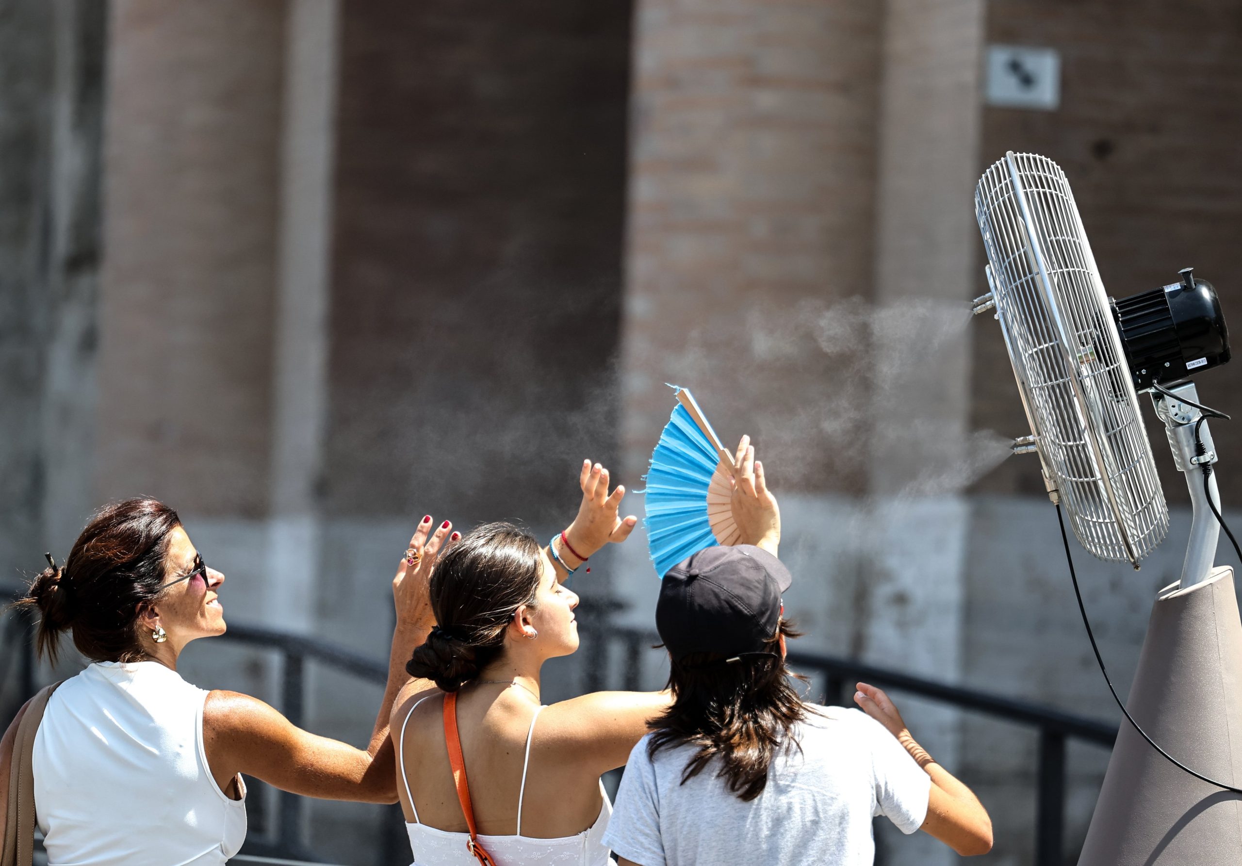 Turistas se refrescan frente a un ventilador cerca del Coliseo, en Roma, Italia, el 27 de junio de 2025.