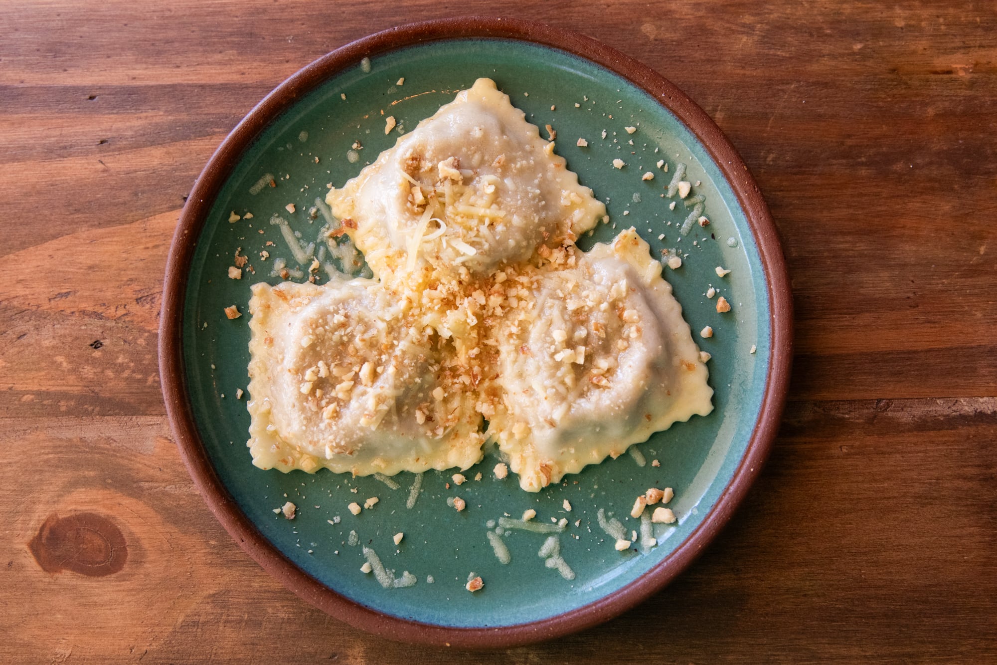 Ravioles de osobuco, con salsa de manteca artesanal, nueces tostadas partidas y queso parmesano reserva.