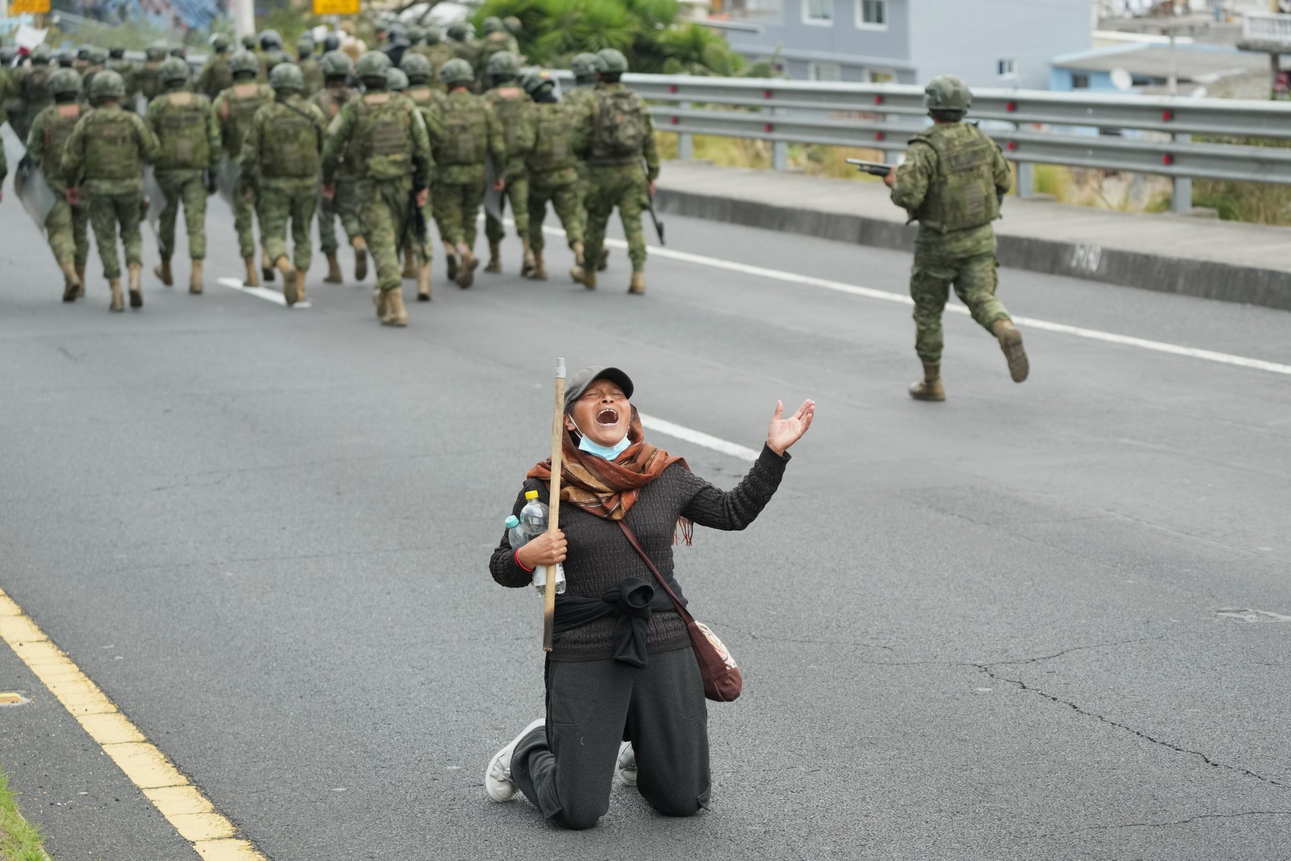 Una manifestante se arrodilla en medio de la protesta por el precio del diésel, mientras los soldados se movilizan