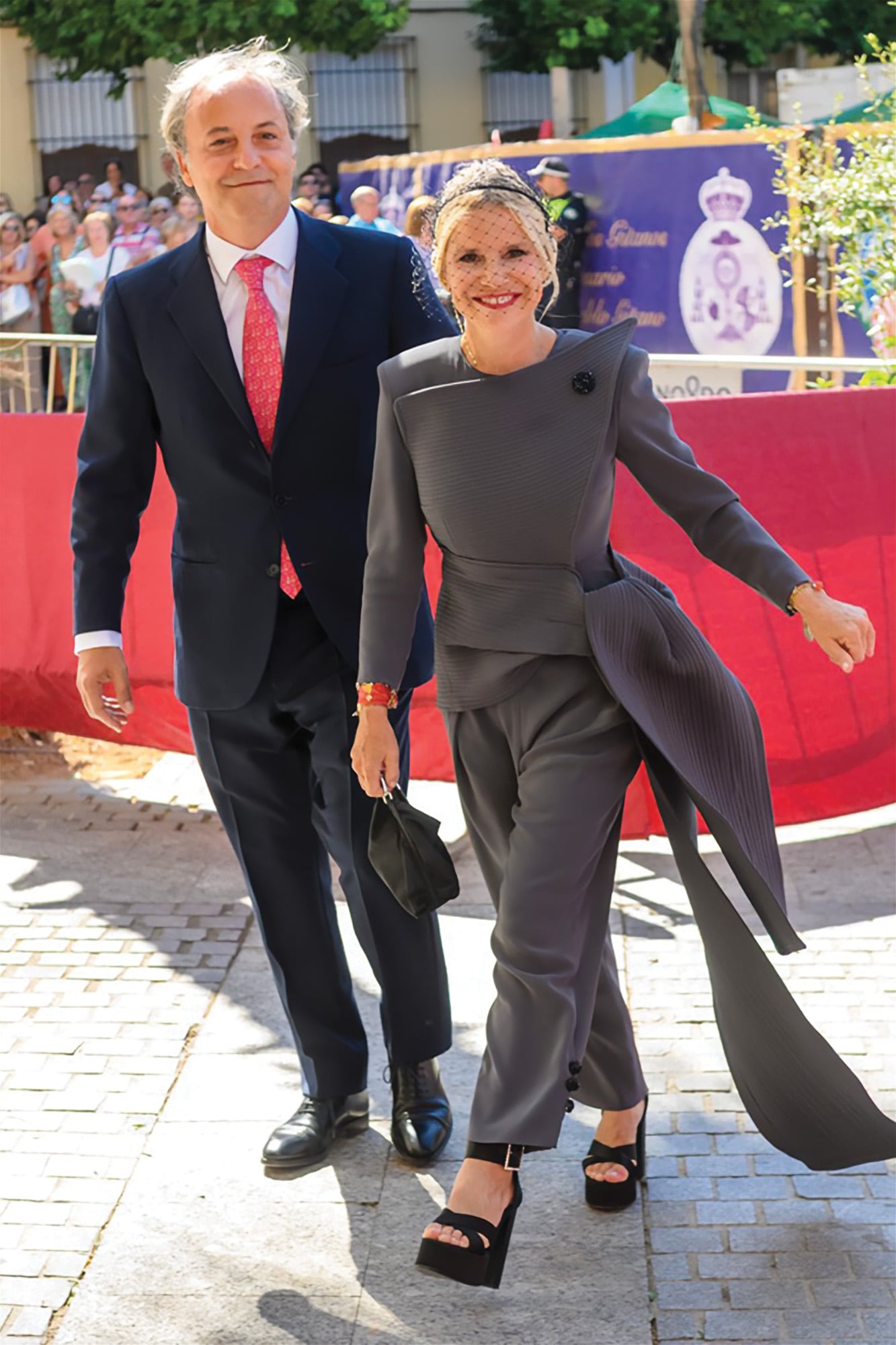 Enfundada en un conjunto de dos piezas  -chaqueta de líneas asimétricas con cruce lateral y pantalón al tobillo, y, además, un tocado de red–, firmado por el diseñador gallego Roberto Diz, Eugenia Martínez de Irujo, duquesa de Montoro y hermana del novio, llega la iglesia acompañada por su marido, el empresario musical Narcís Rebollo