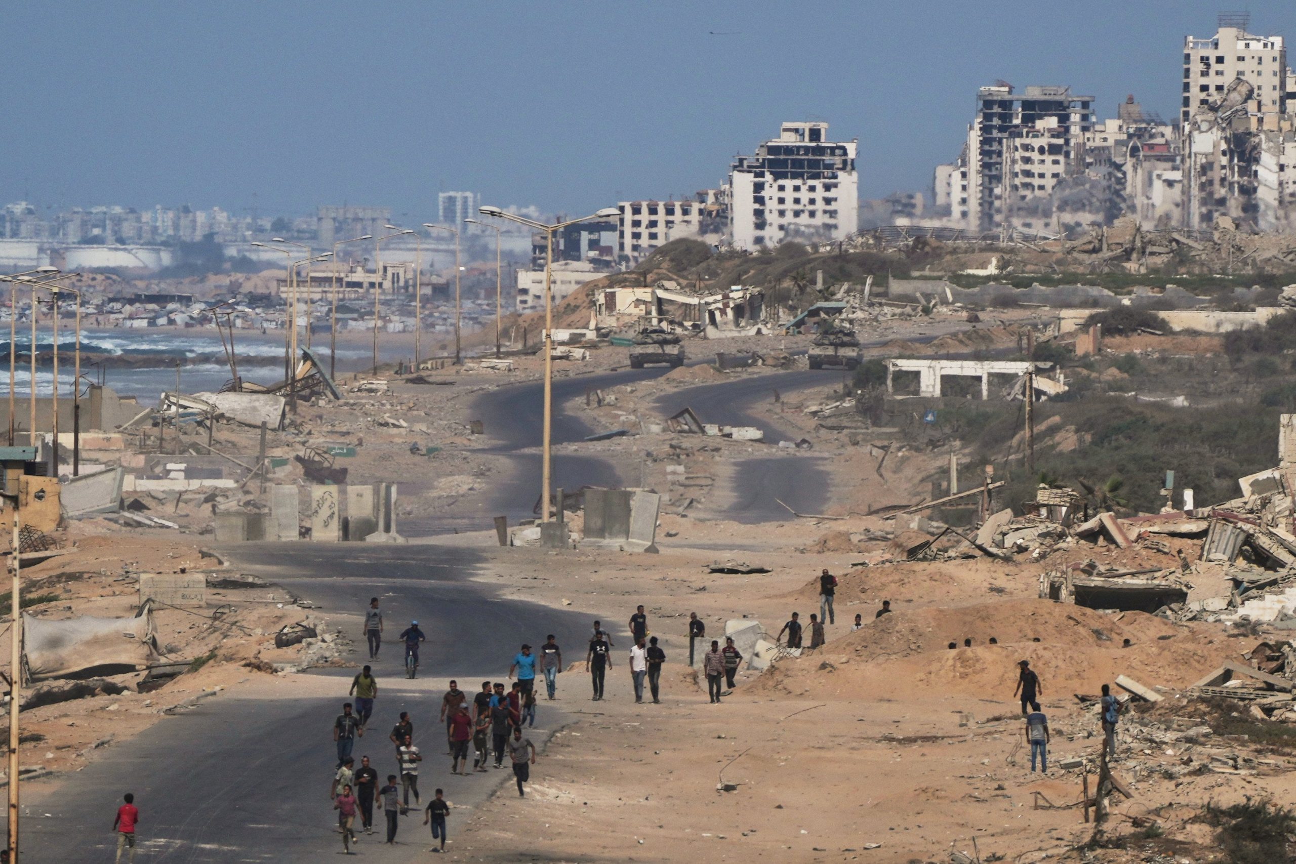 Tanques israelíes bloquean la carretera costera hacia la ciudad de Gaza mientras palestinos desplazados se reúnen en la ruta junto al mar, el jueves 9 de octubre de 2025.