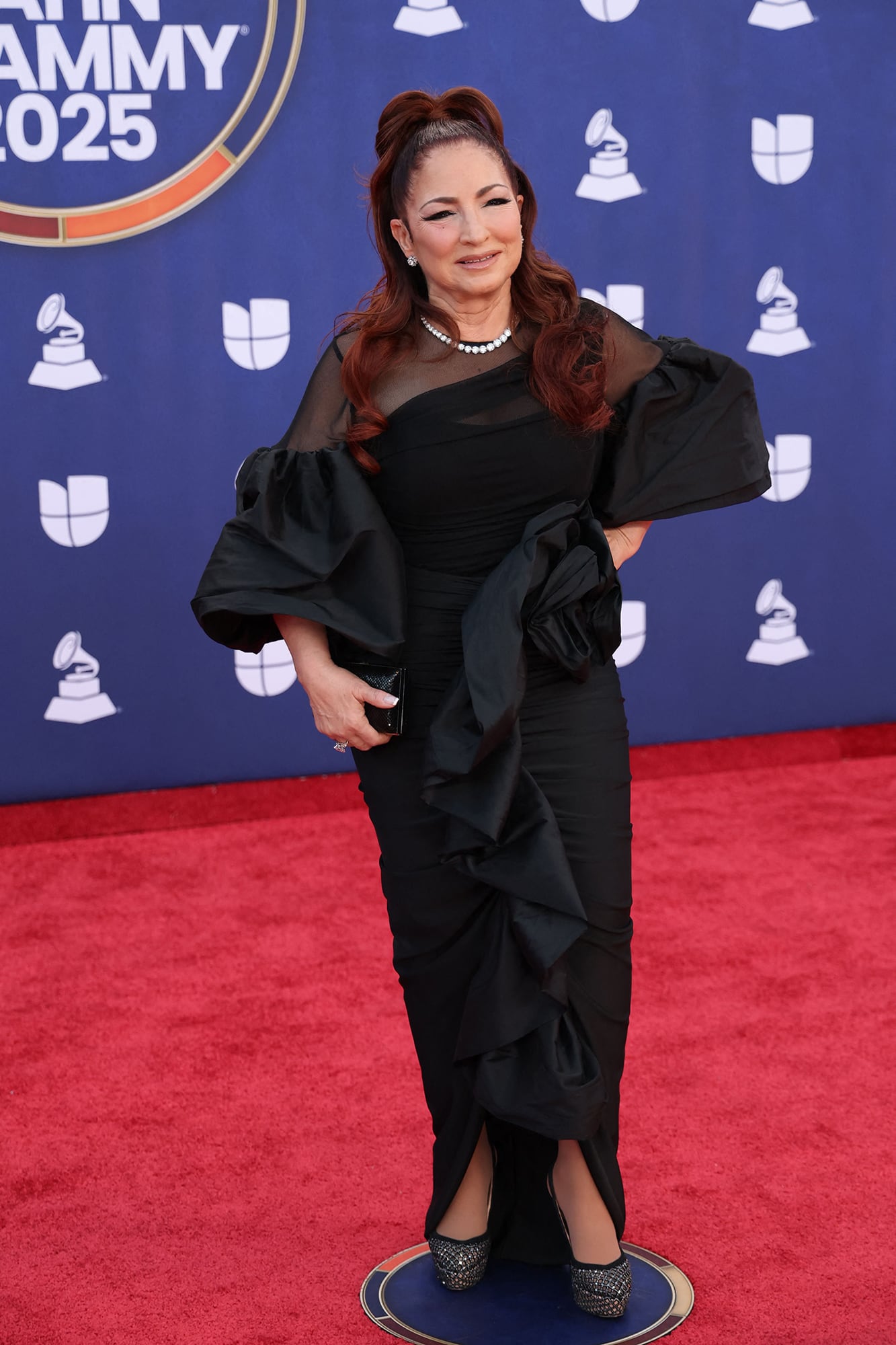 Gloria Estefan, nominada por su álbum Raíces, sorprendió con un modelo que combinó mangas abultadas, transparencias en el escote y un drapeado en la falda 