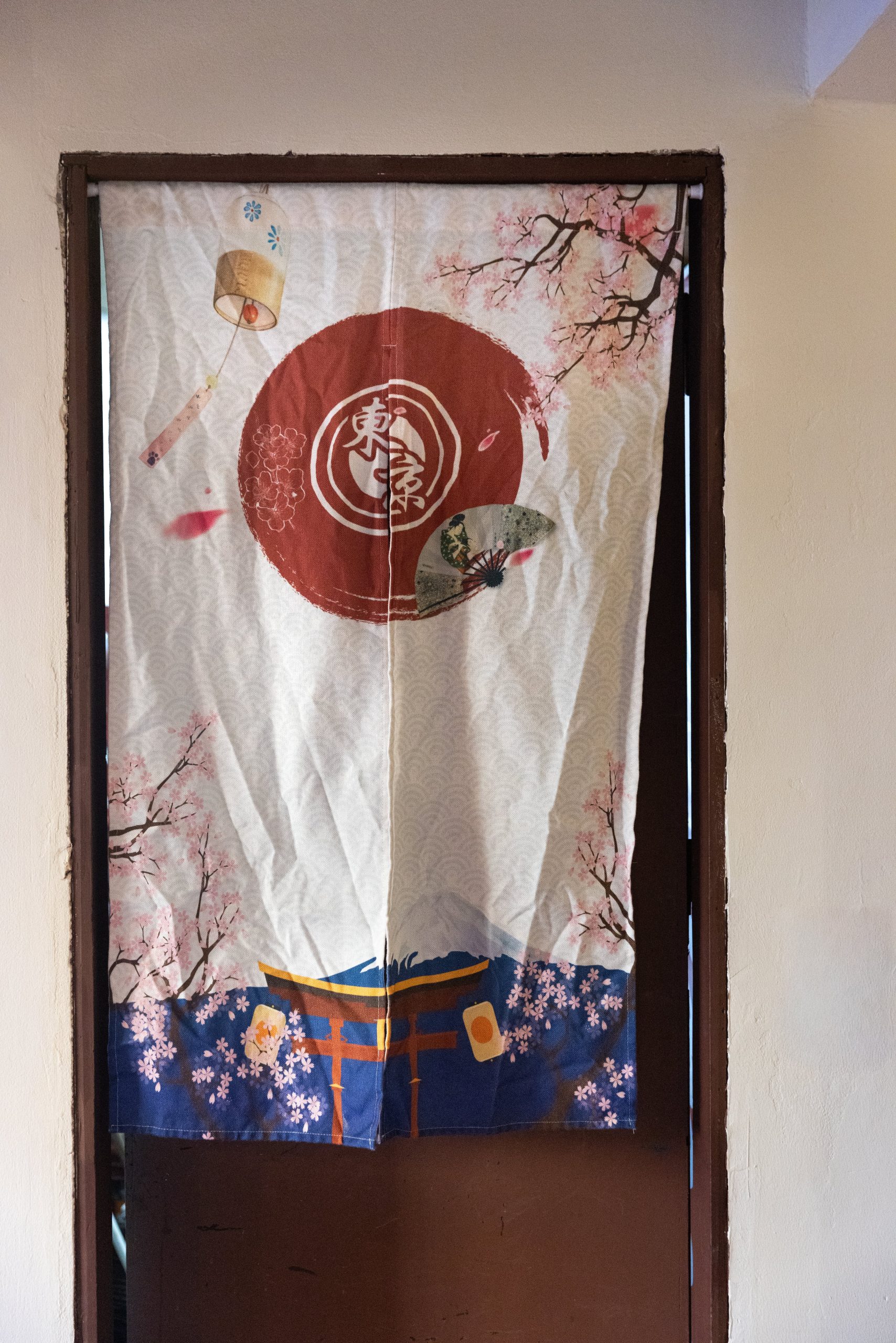 Una de las puertas del local con una cortina japonesa
