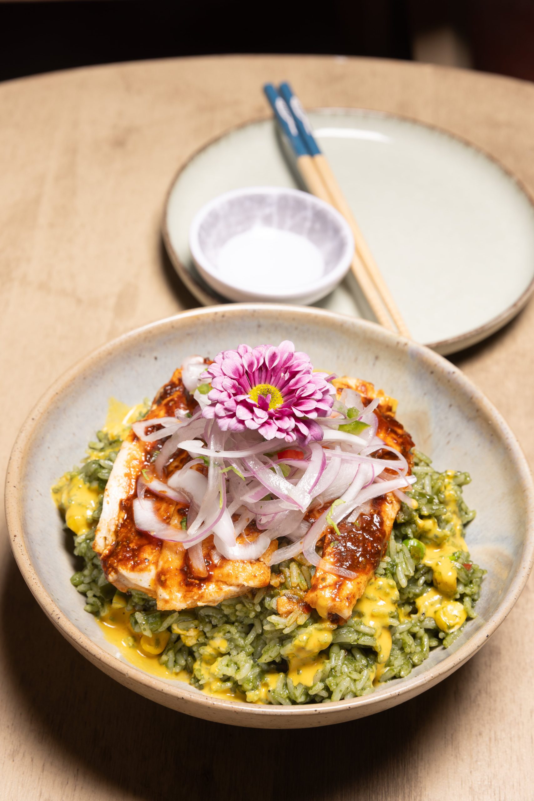 Raisu, plato de arroz verde peruano aderezado con cilantro, ají amarillo, choclo, arvejas, con mero sellado en salsa anticuchera y salsa huancaina