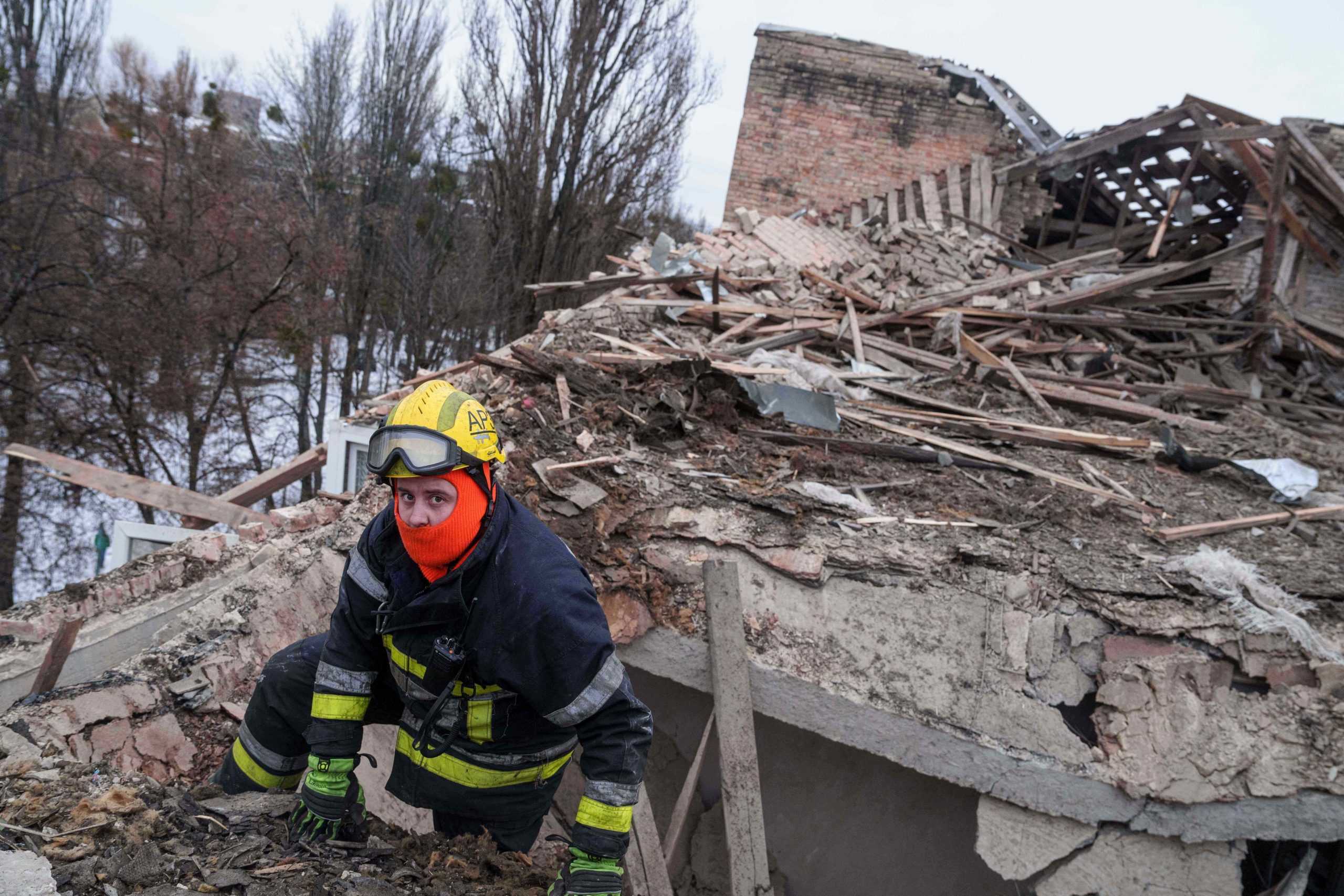 Un rescatista trepado al techo destruido de un edificio impactado por el bombardeo ruso sobre Kiev
