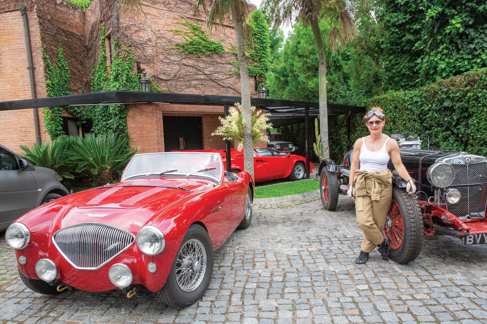 En la puerta de su casa, Margarita con dos de sus autos, un MG SA de 1936 y un Austin Healey 100 de 1956