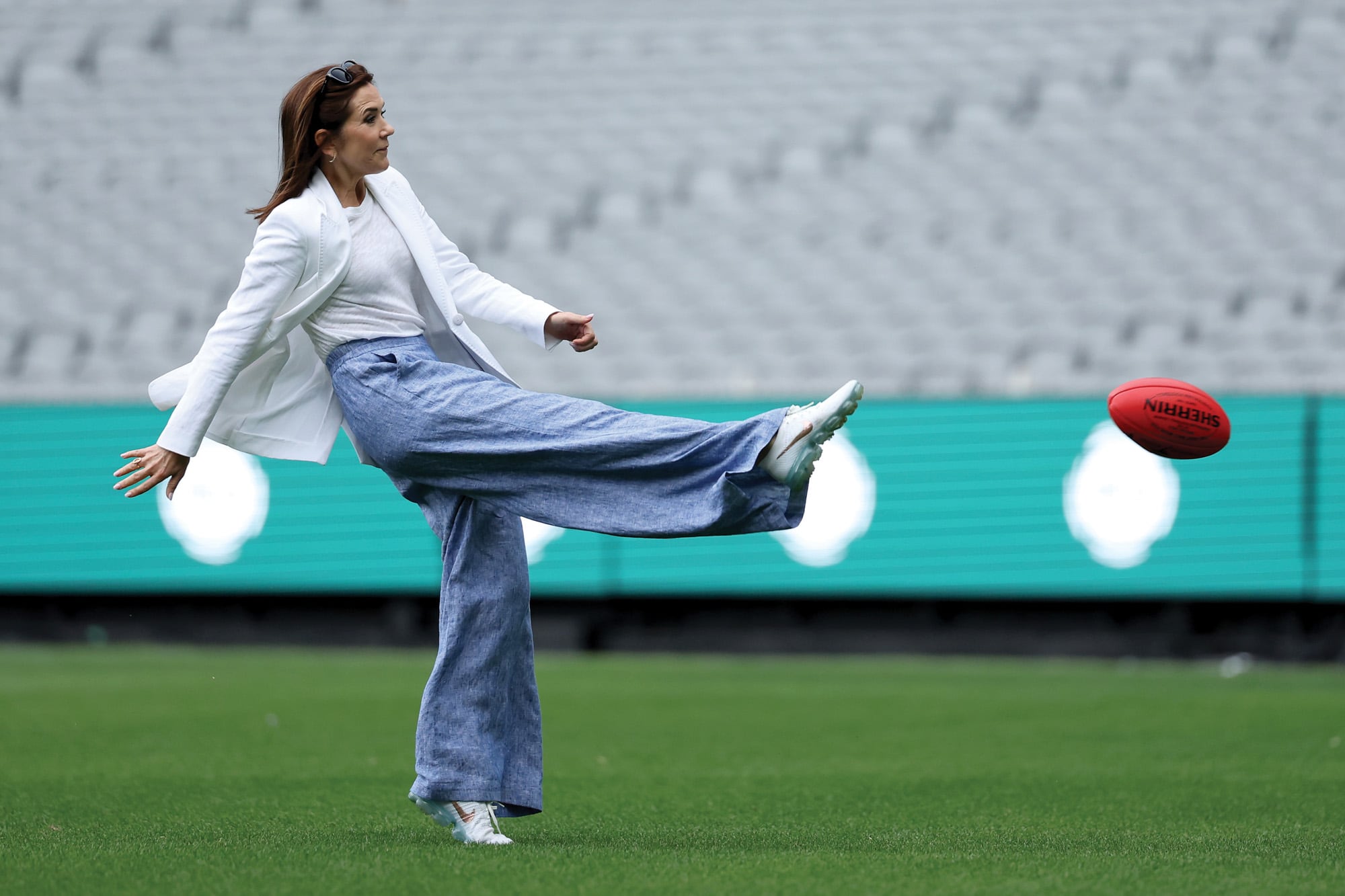 Con un look de pantalón de lino, pateó una pelota de fútbol australiano