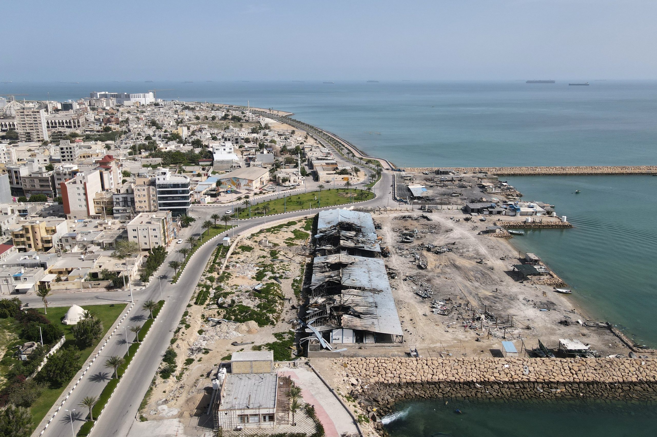 Con barcos de fondo en el estrecho de Ormuz, se observan daños en un muelle pesquero del puerto de la isla de Qeshm, Irán, el 13 de abril de 2026.
