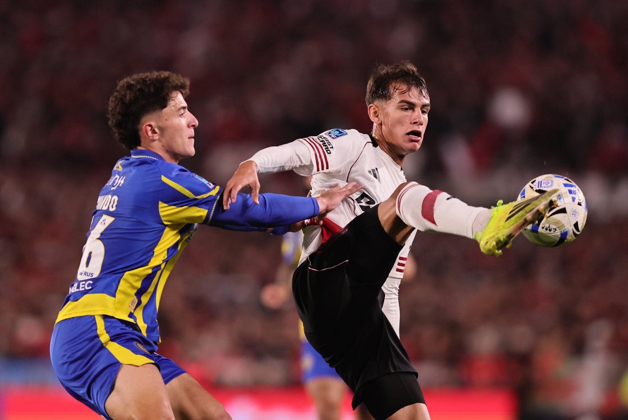 Joaquín Freitas aguanta la pelota ante la marca de Ovando, de Rosario Central