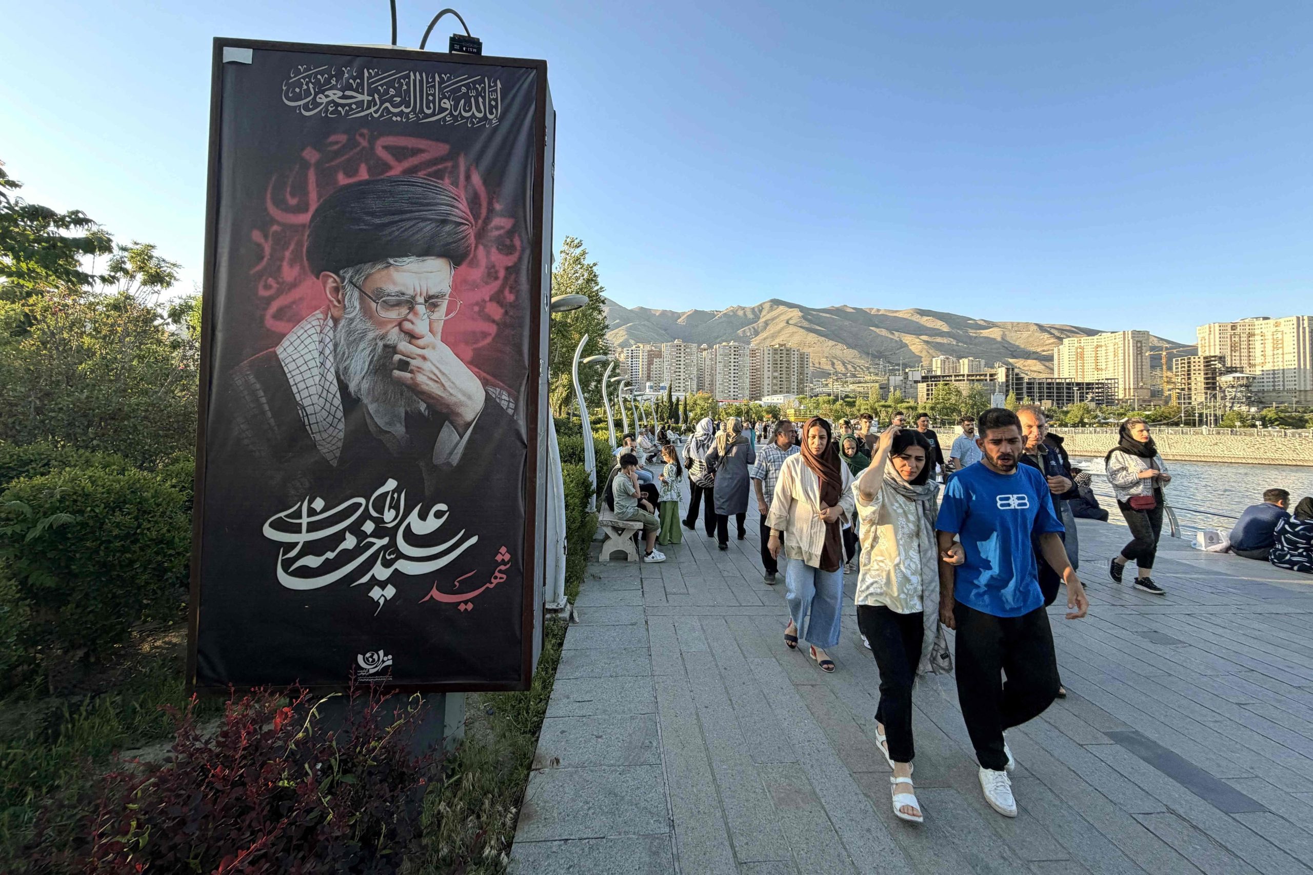 Transeúntes pasan por el costado de una imagen del martirizado ayatollah Khamenei