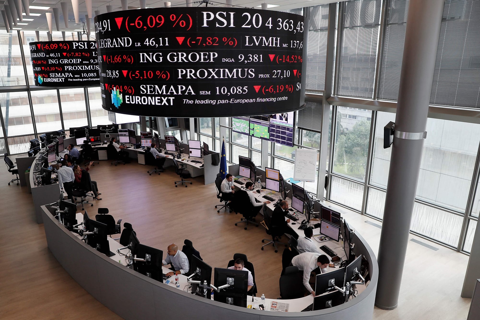 Empleados trabajan mientras las pantallas muestran noticias y cotizaciones en los servicios de la Bolsa Euronext, en el distrito financiero de La Défense, en París.