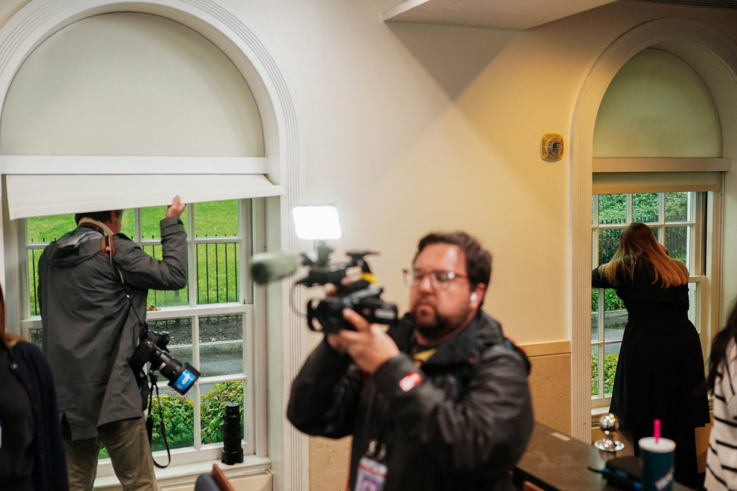 Periodistas miran por las ventanas de la sala de prensa de la Casa Blanca tras escucharse disparos en las inmediaciones este 23 de mayo de 2026. (Foto: Nathan Howard/REUTERS)
