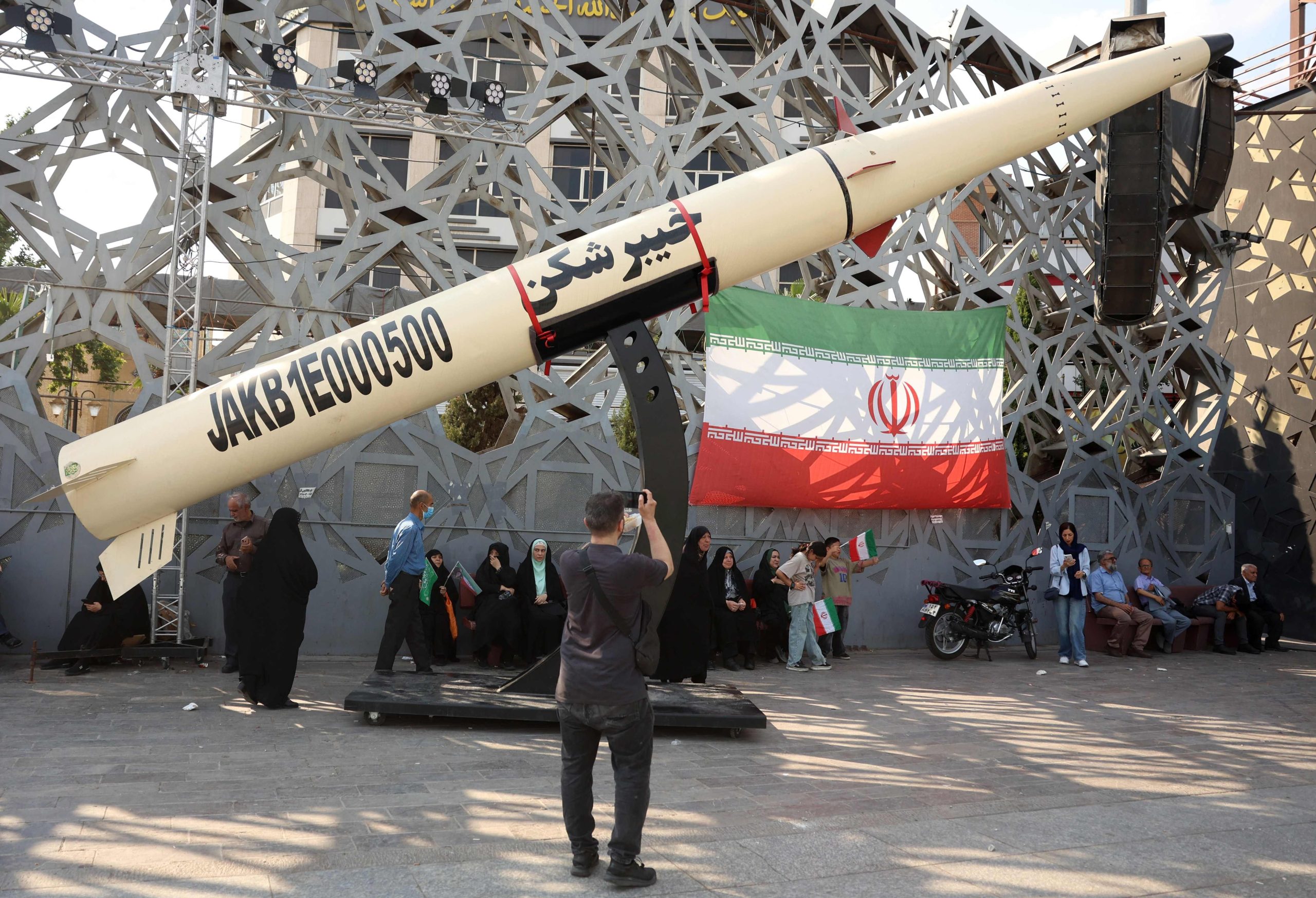 Un grupo de iraníes, junto a una representación de un misil Kheibar durante una concentración en apoyo al líder supremo del país, Mojtaba Khamenei, en Teherán