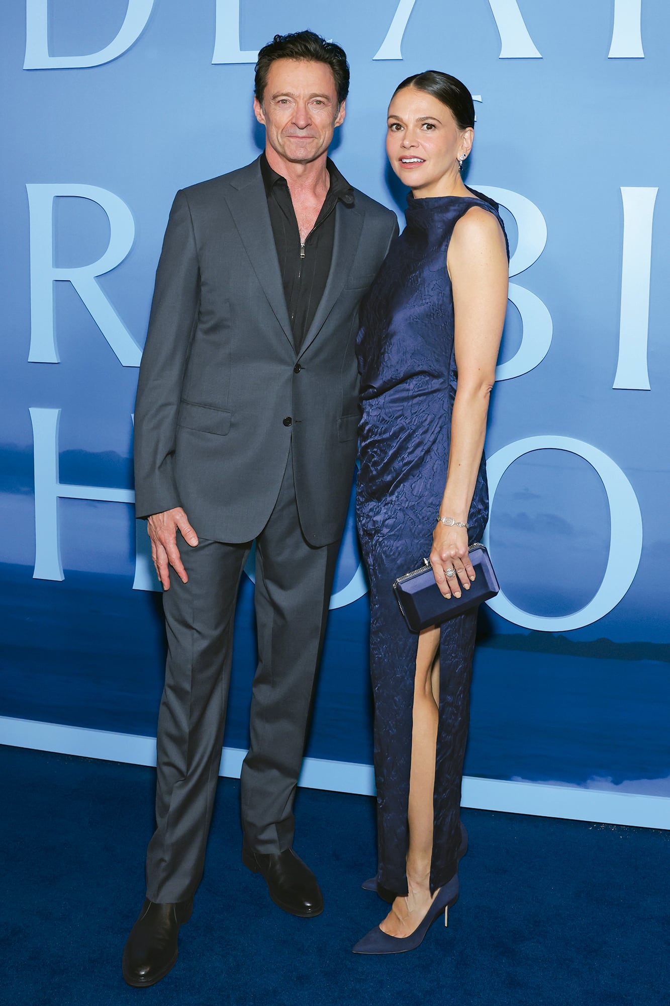 Hugh Jackman posó con impecable traje de Brioni y camisa sin corbata, mientras que Sutton eligió un vestido azul de Marina Moscone, con tajo lateral y drapeados