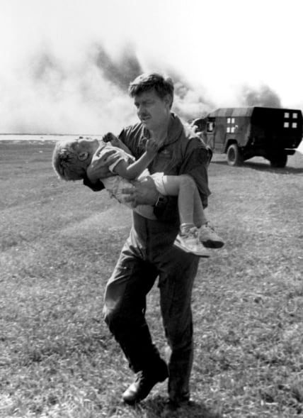 El teniente coronel Dennis Nielsen lleva en brazos a Spencer Bailey, de tres años, después del accidente del vuelo 232. La fotografía, tomada por Gary Anderson, se convirtió en uno de los símbolos del rescate
