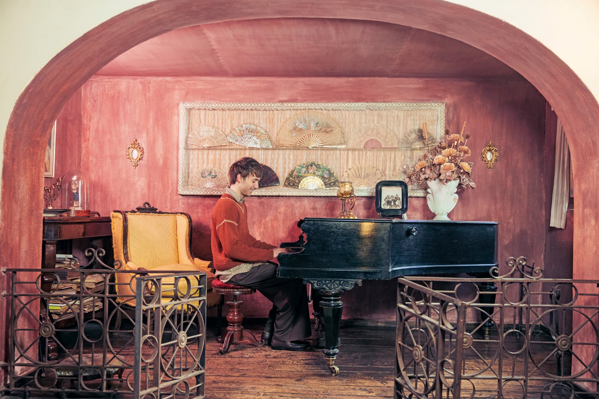 Bajo un arco de líneas coloniales, el actor y cantante se sienta al piano traído de Viena. Detrás, se enmarcan fabulosos abanicos de marfil y carey pintados a mano