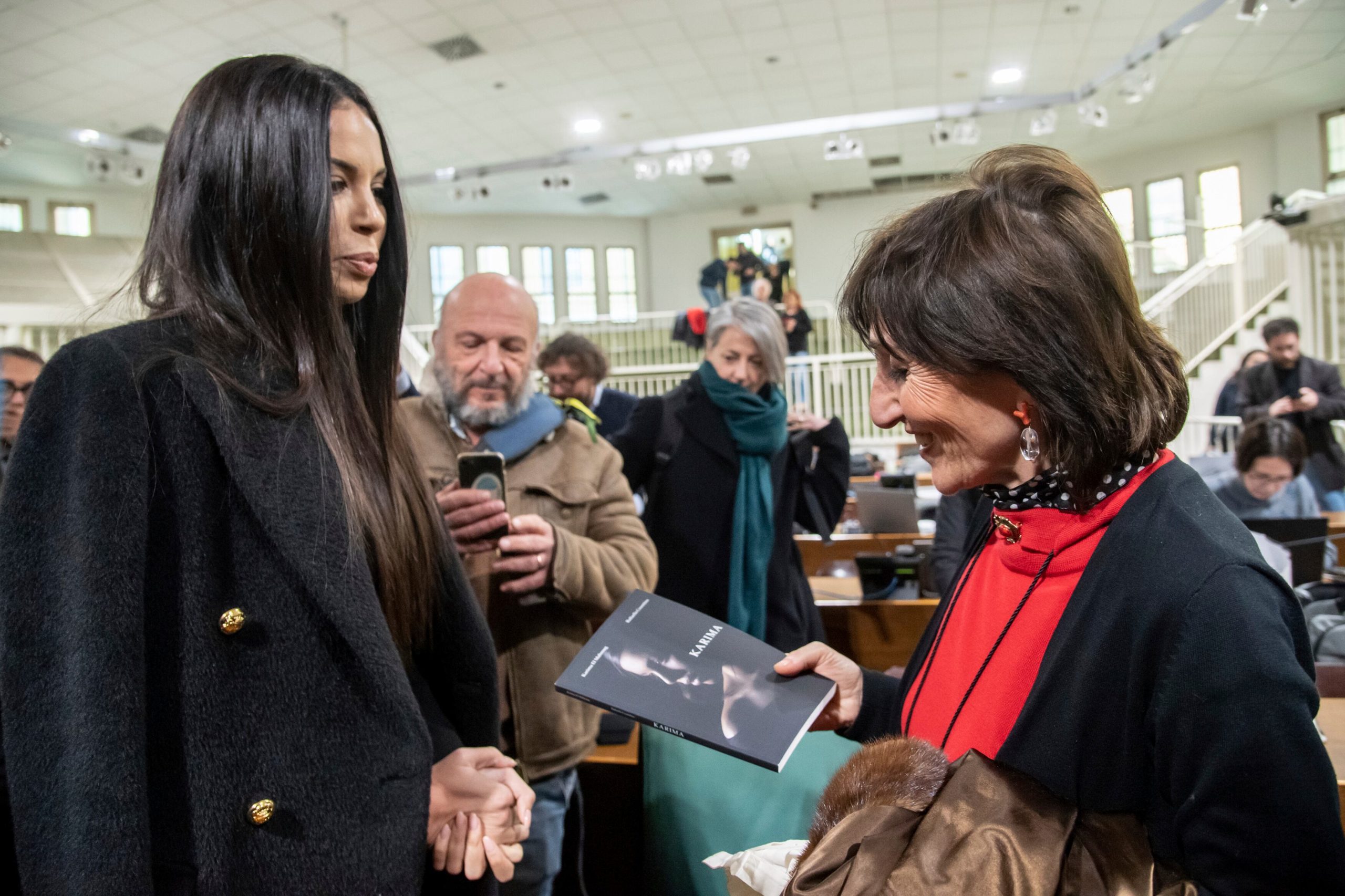 Karima el Mahroug, alias Ruby Rubacuori, una de las mujeres que asistían a las tristemente célebres fiestas sexuales del expremier italiano Silvio Berlusconi, presenta su libro a la fiscal Tiziana Siciliano, derecha, durante el juicio en la cárcel de San Vittore, Milán, miércoles 15 de febrero de 2023. (Claudio Furlan/LaPresse via AP)