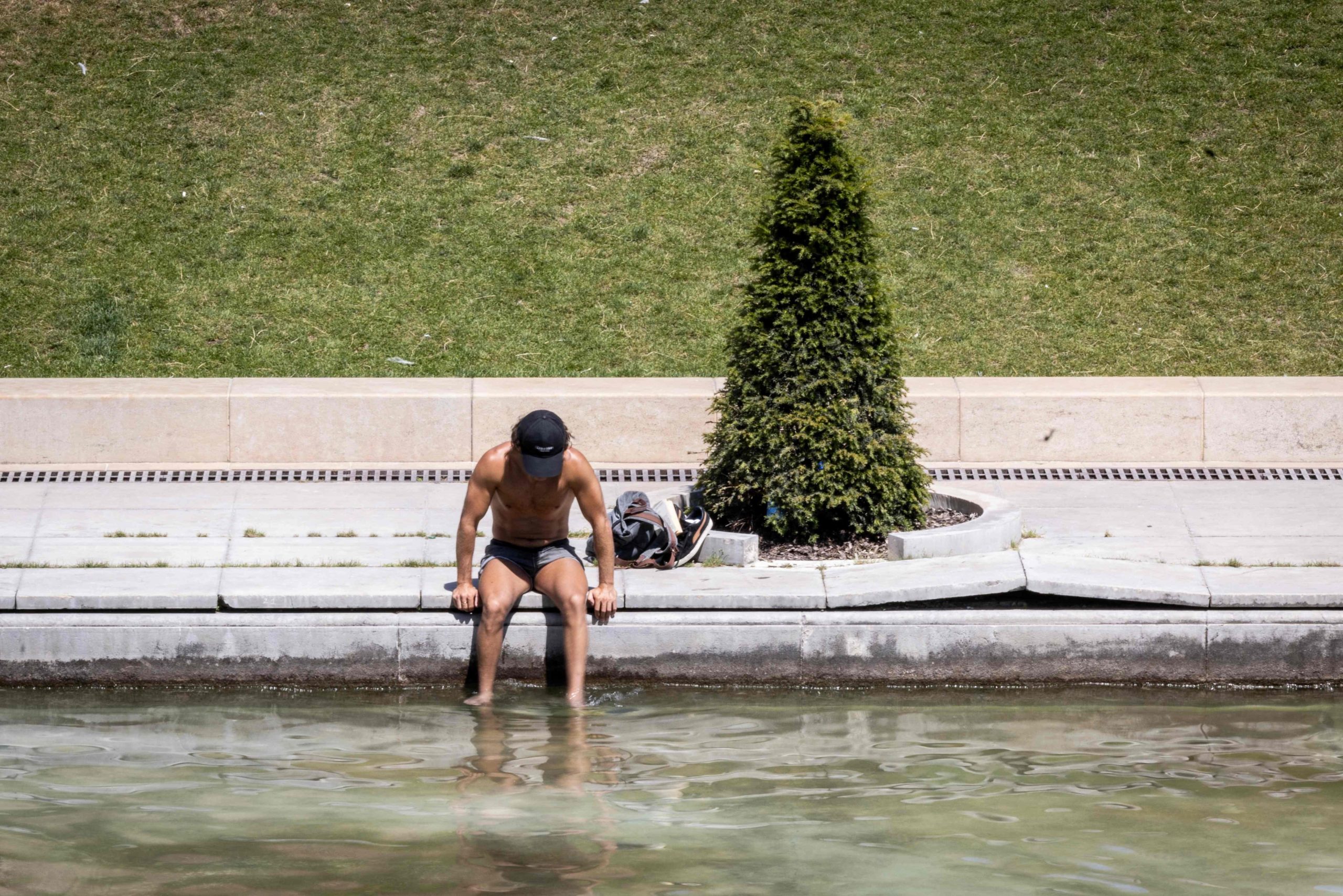 TOPSHOT - A man cools off by a pool at the Jardin du Trocadero, in Paris on July 10, 2026, as a new heatwave hits France. (Photo by Behrouz MEHRI / AFP)