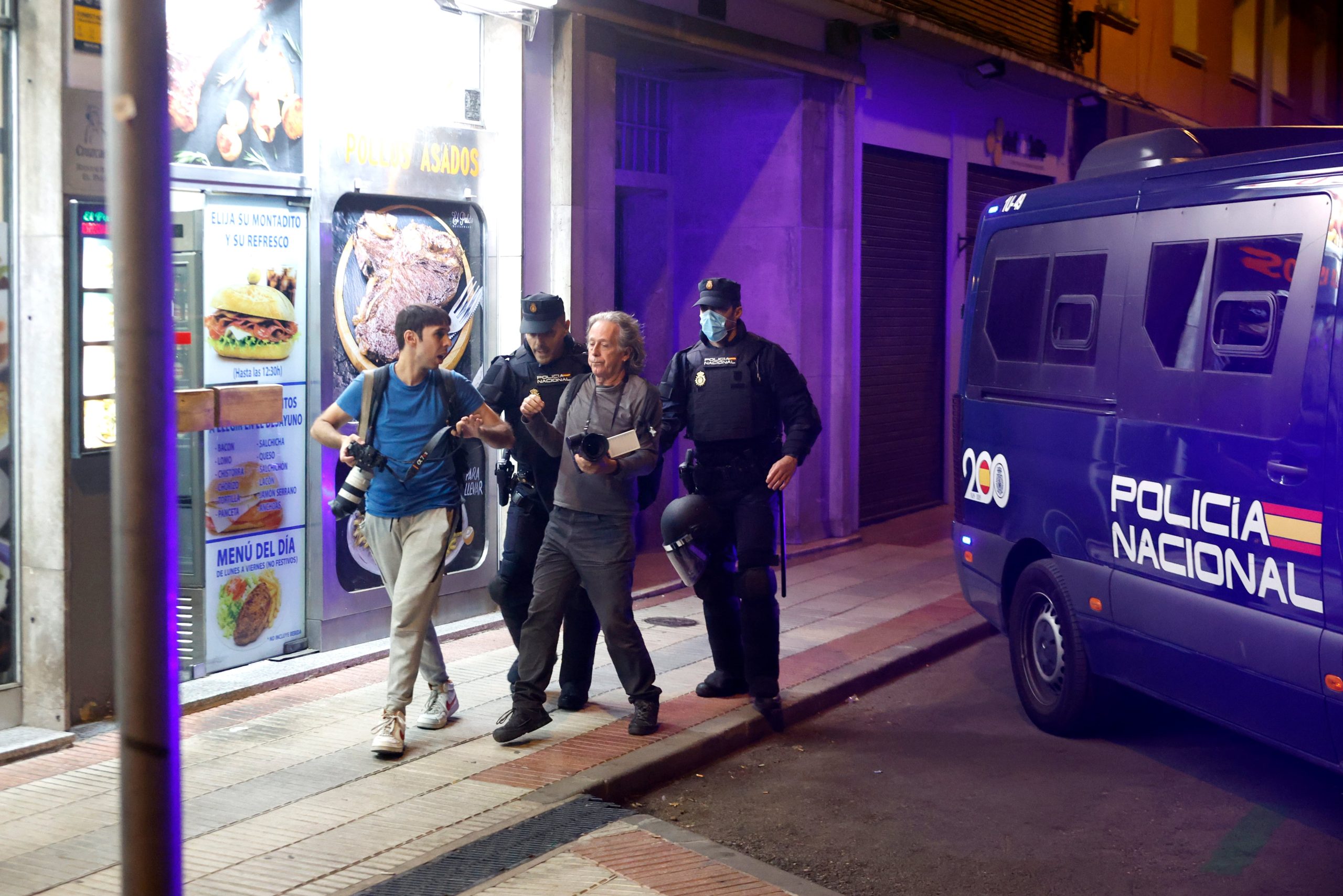Agentes de la policía alejan del portal de Maricarmen a dos fotógrafos.