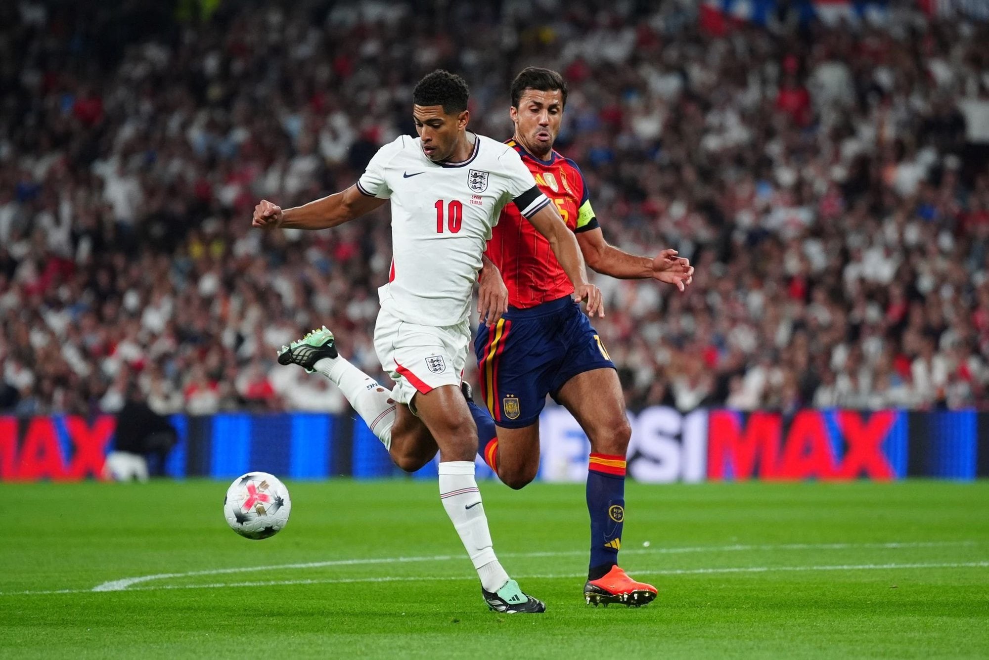 Bellingham cubre la pelota ante Rodri