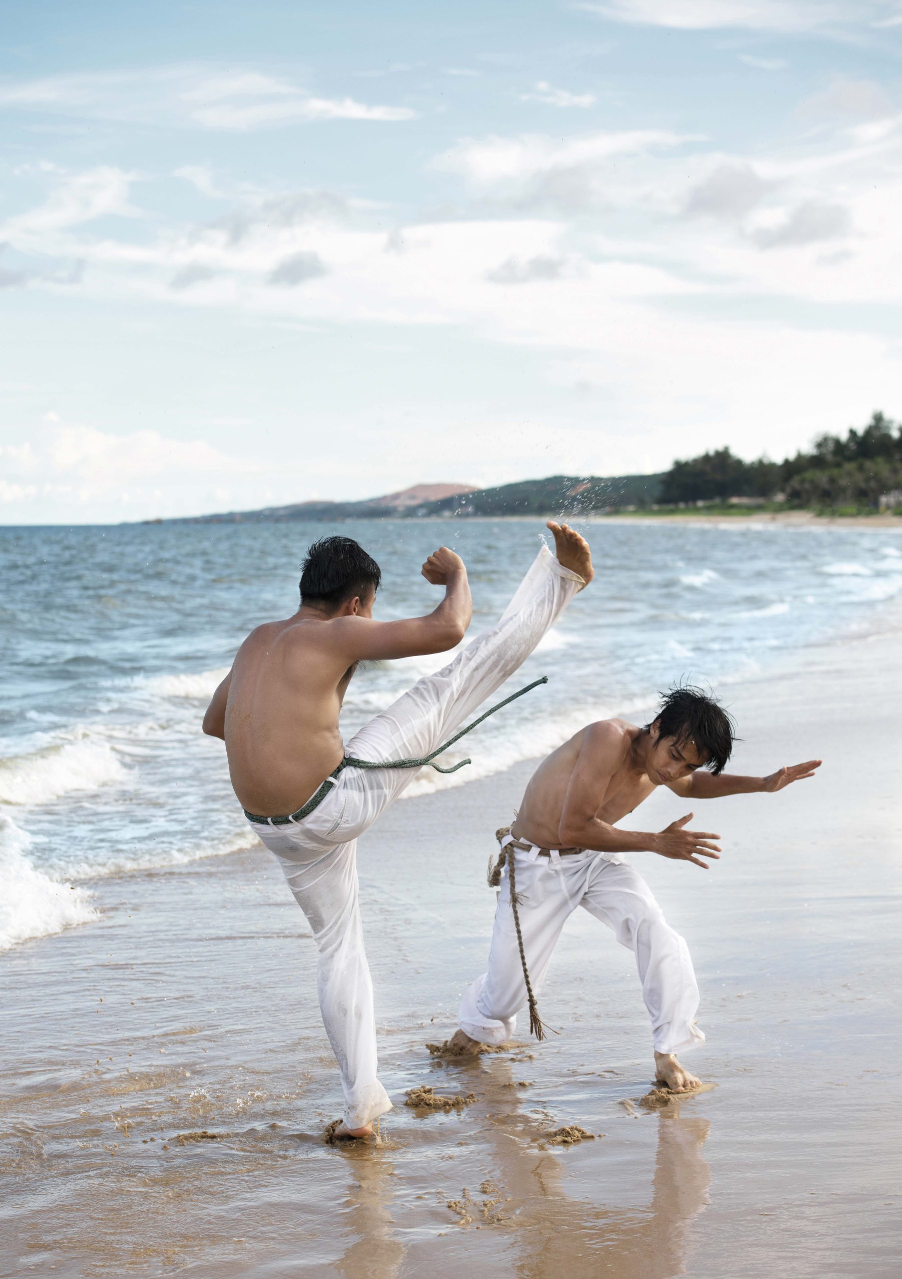 Jóvenes practicando capoeira en la playa.