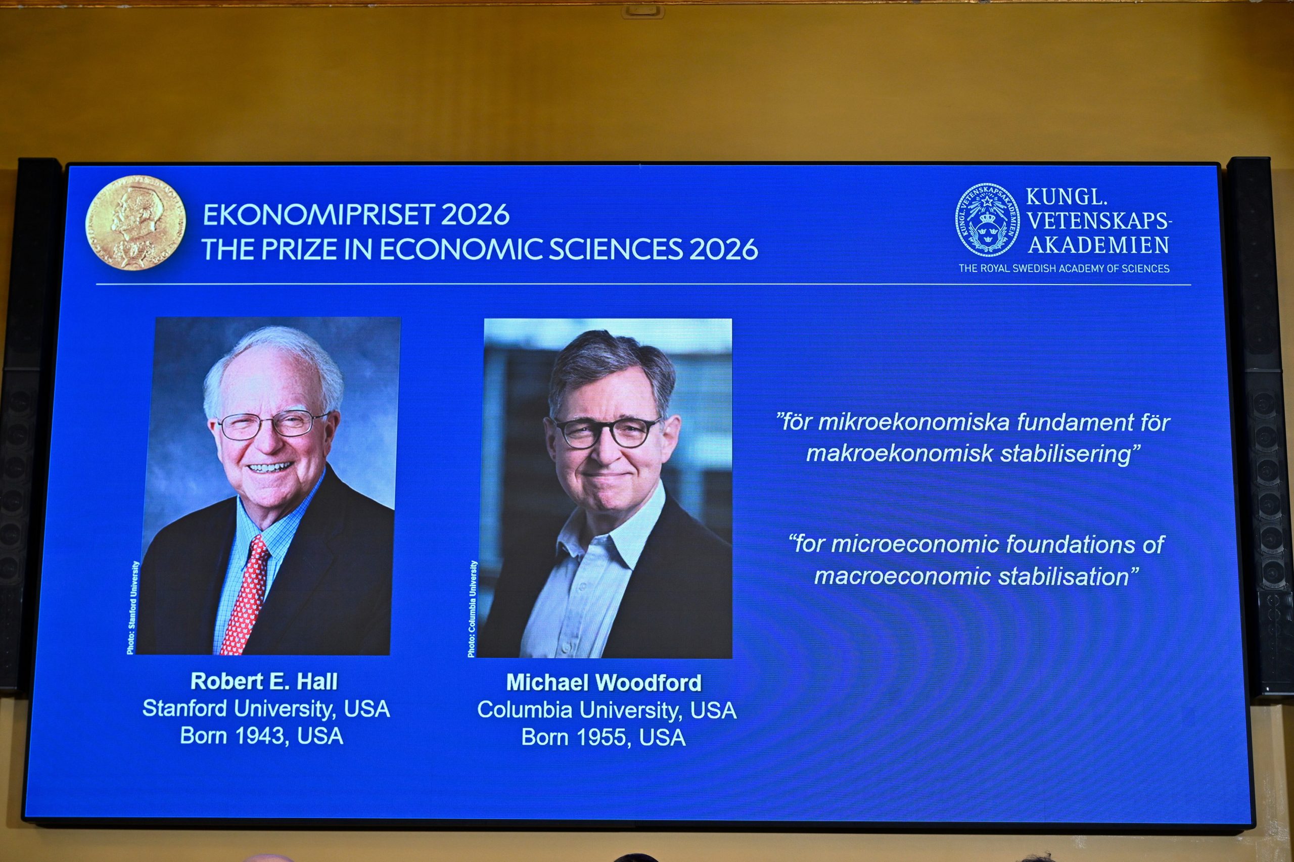 Retratos de Robert E. Hall y Michael Woodford se ven en la pantalla mientras se anuncia que han recibido el Premio del Banco de Suecia de Ciencias Económicas en Memoria de Alfred Nobel, en la Academia Sueca de Ciencias en Estocolmo, Suecia, el lunes 12 de octubre de 2026. (Anders Wiklund/TT News Agency via AP)