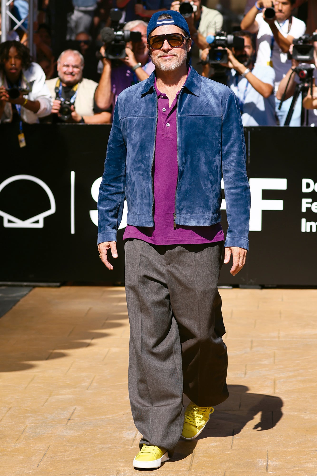 Para su llegada a San Sebastián, el actor articuló su outfit alrededor de una chaqueta de gamuza azul de Zegna y pantalones de la misma firma, que combinó con una remera polo Ralph Lauren, zapatillas de Prada, gafas de sol también de Prada y un cap de Hermès